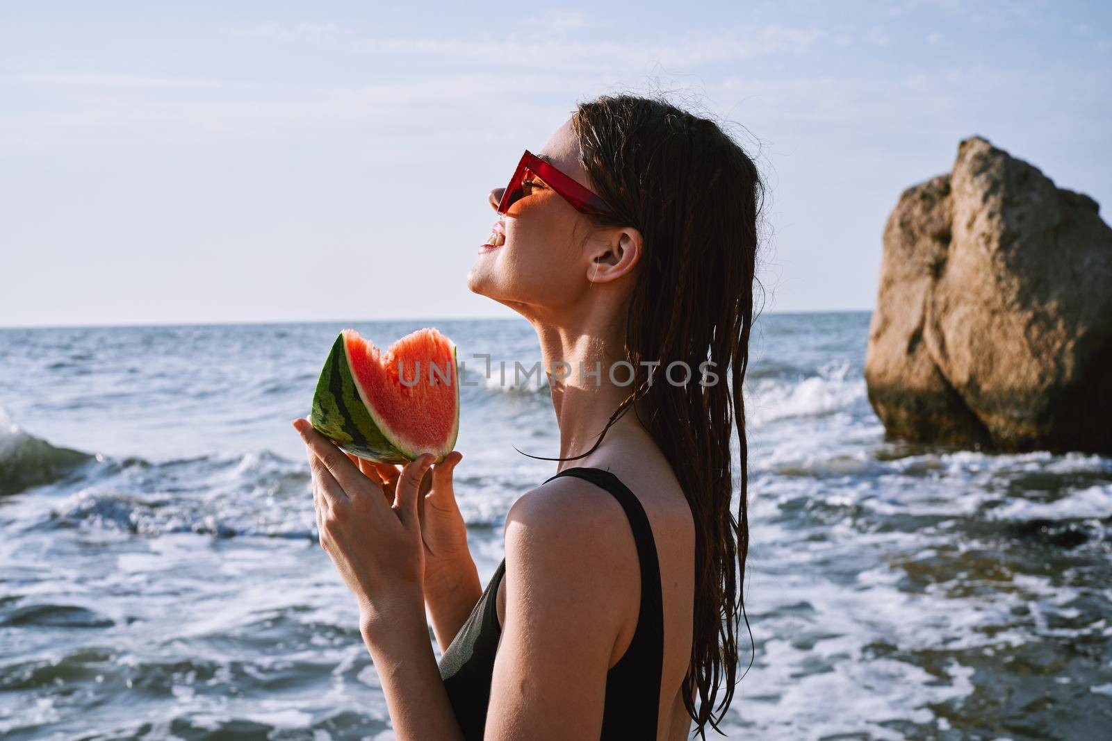 woman in black swimsuit with watermelon by the ocean. High quality photo