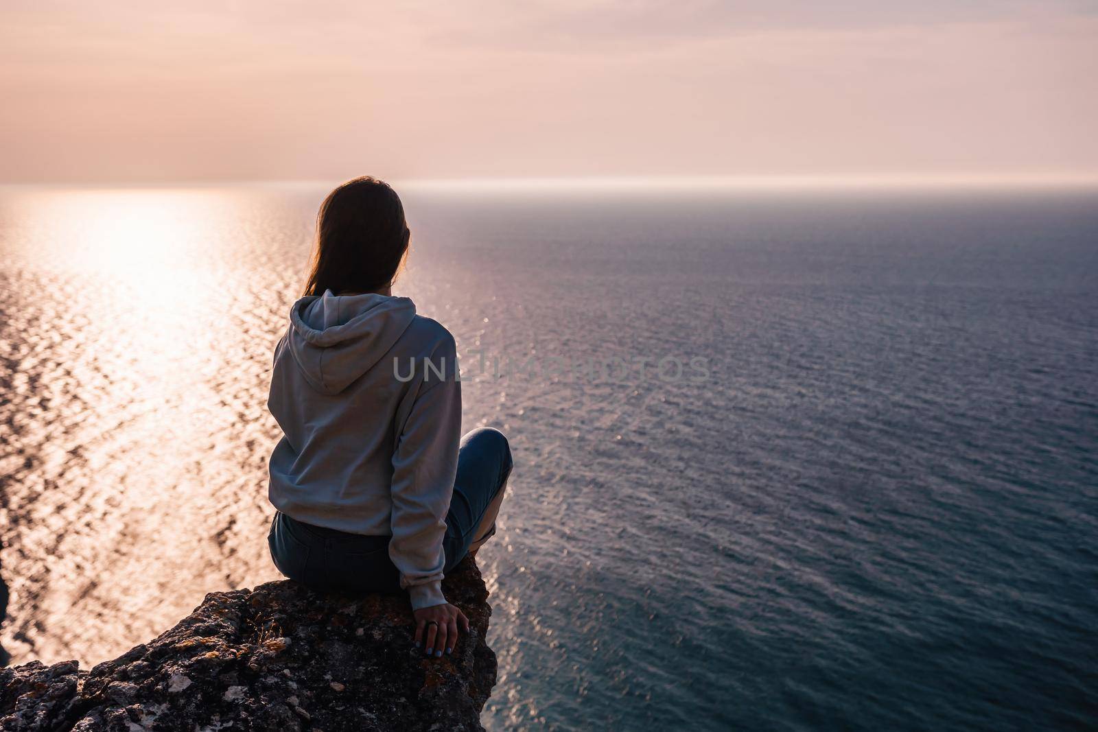 woman traveler drinks coffee with a view of the mountain landscape. A young tourist woman drinks a hot drink from a cup and enjoys the scenery in the mountains. Trekking concept