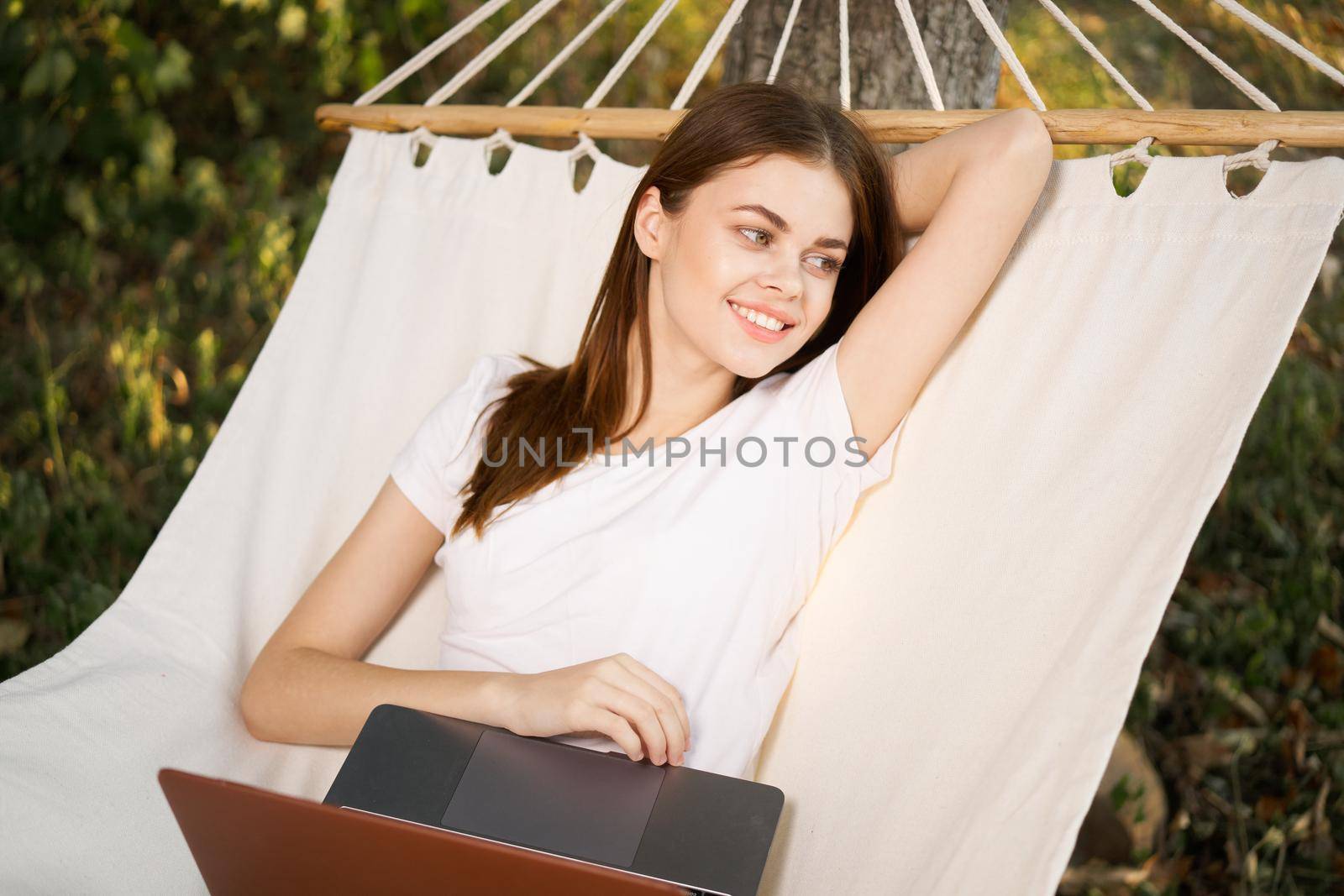 woman with laptop lies in hammock freelance travel. High quality photo