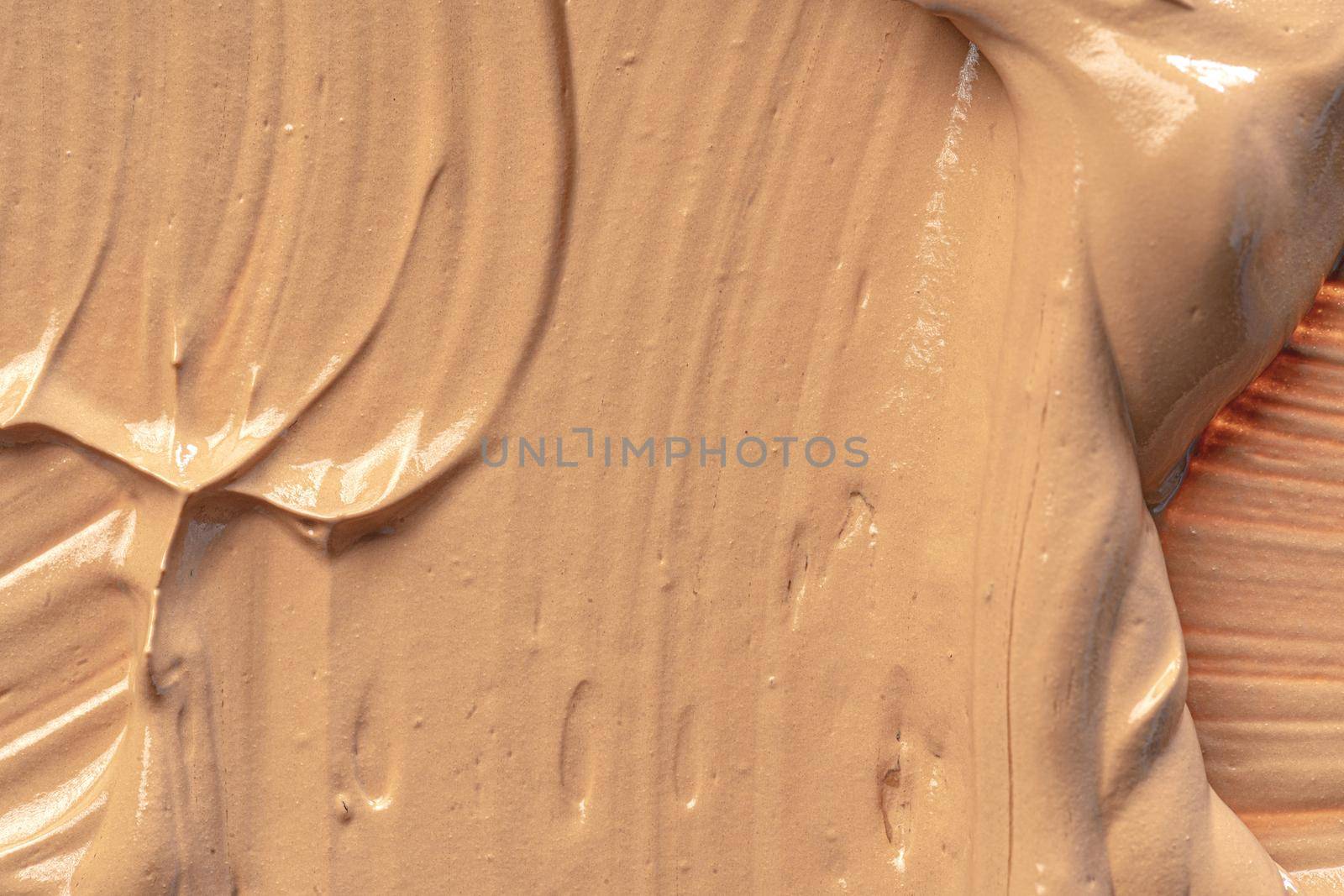 Background of a smudged cream foundation texture, close up