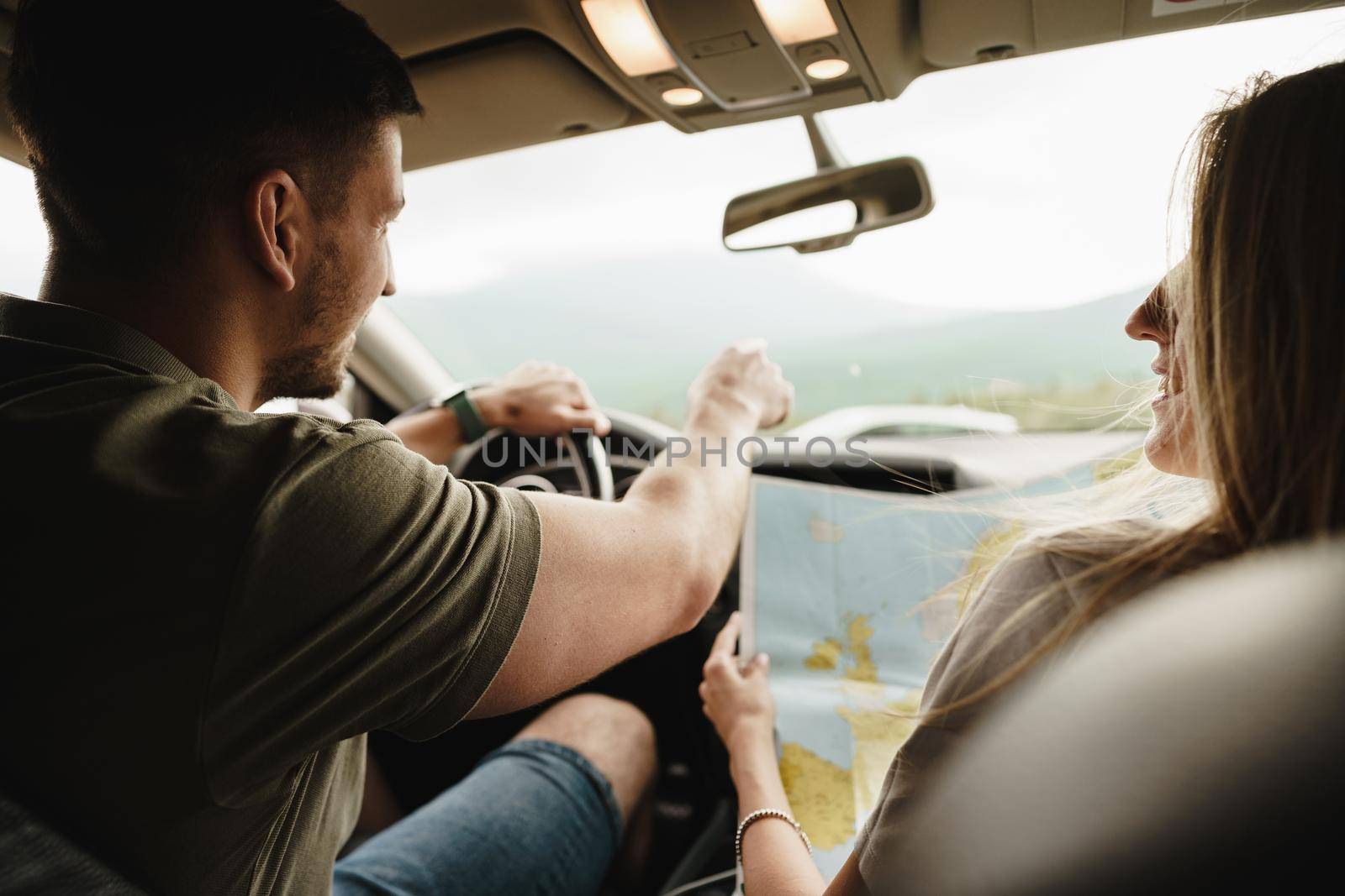 Young loving couple on a road trip using map inside a car, close up