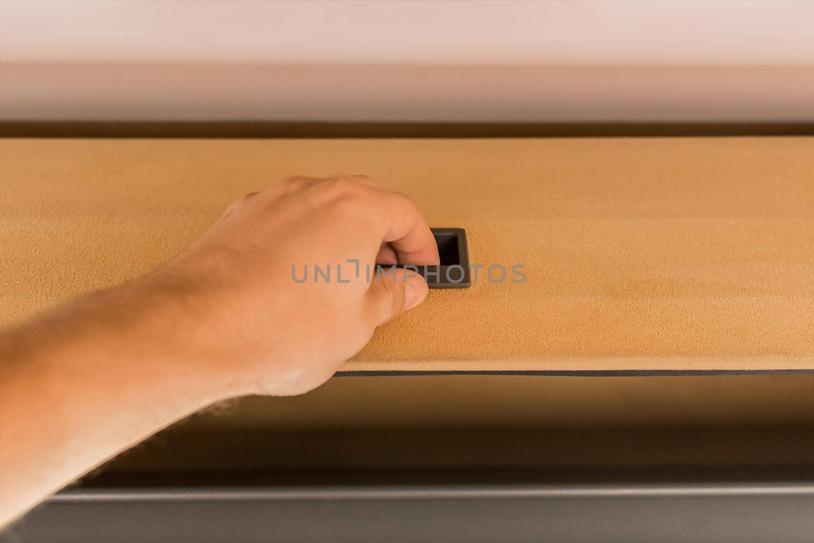 The guy's hand opens or closes the shelf for storing things in the cabin of the bus.