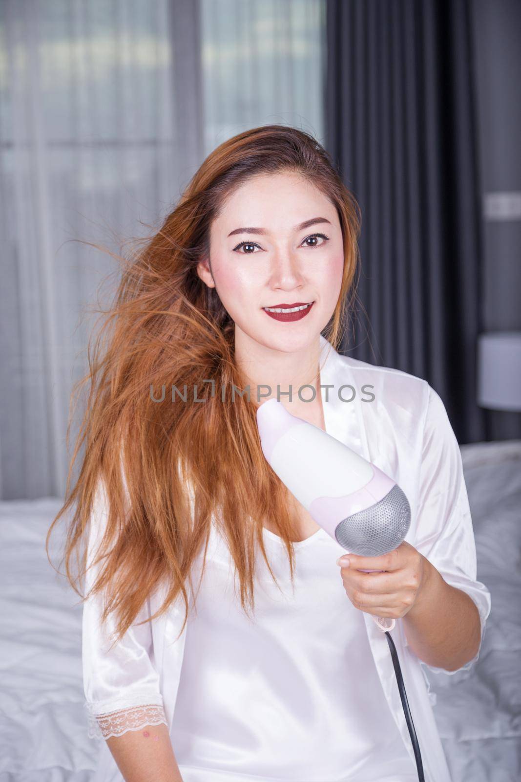 woman using hair dryer in bedroom by geargodz