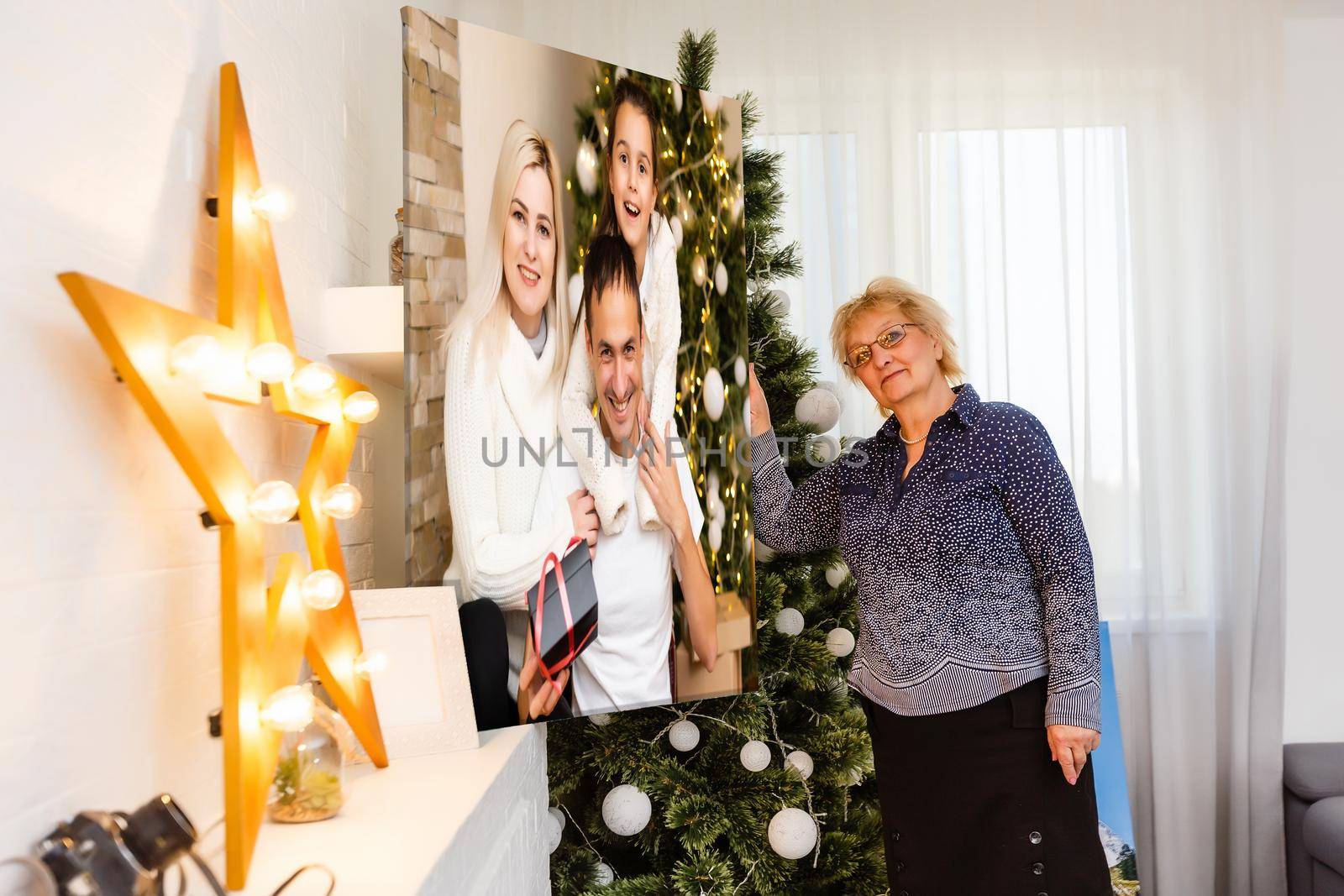 woman holding a photo canvas on the background of a Christmas interior.