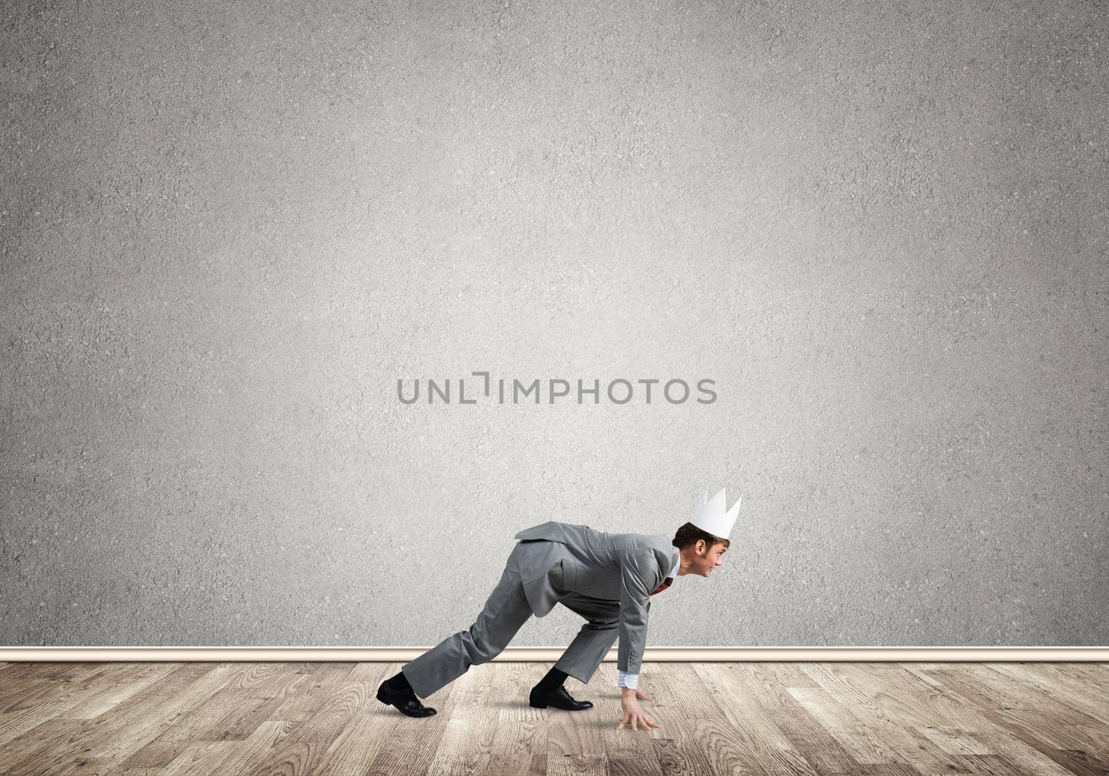 Young handsome businessman wearing white paper crown running in a hurry