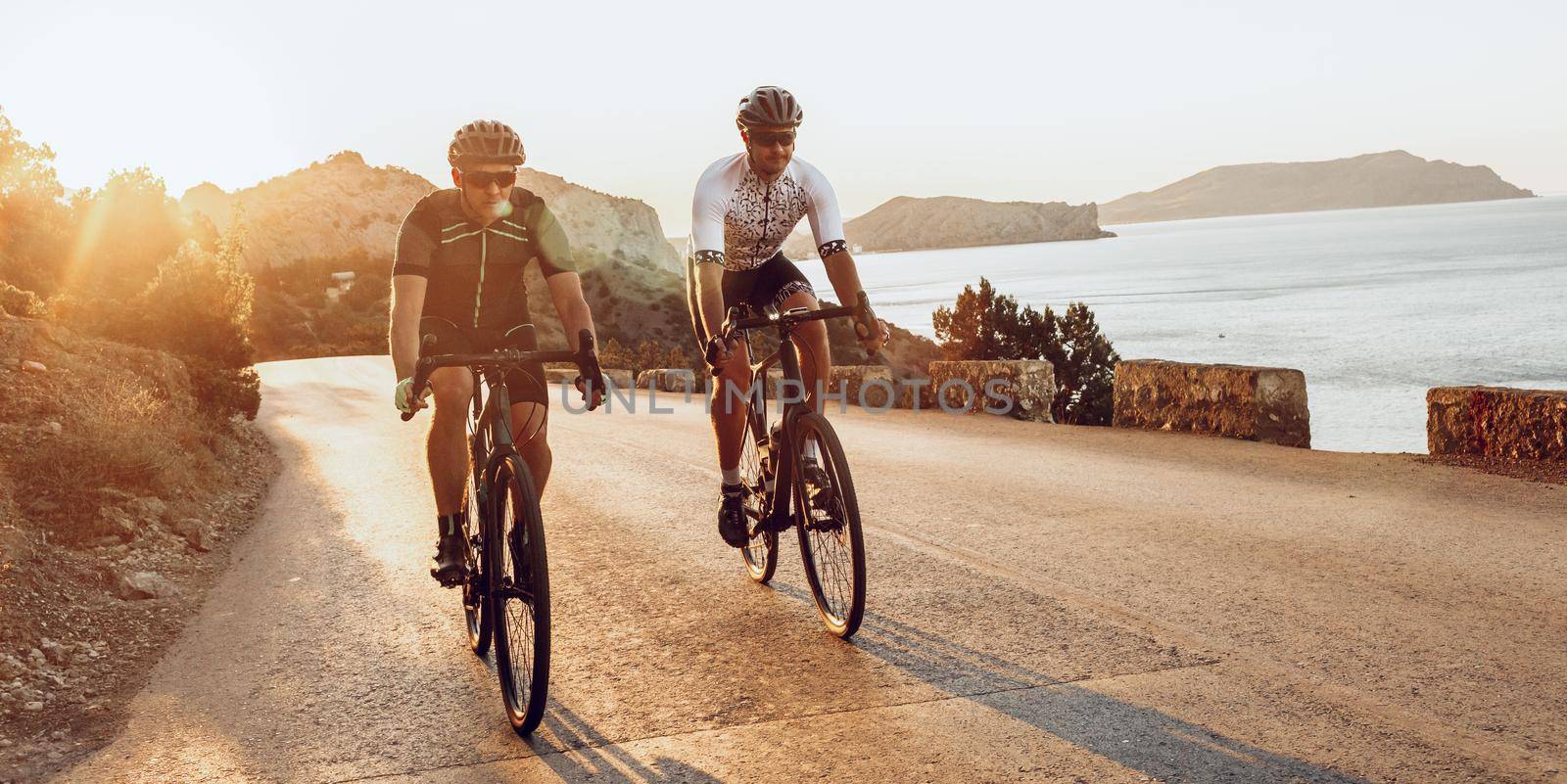 Two professional male cyclists riding their racing bicycles in the morning together on coastal road