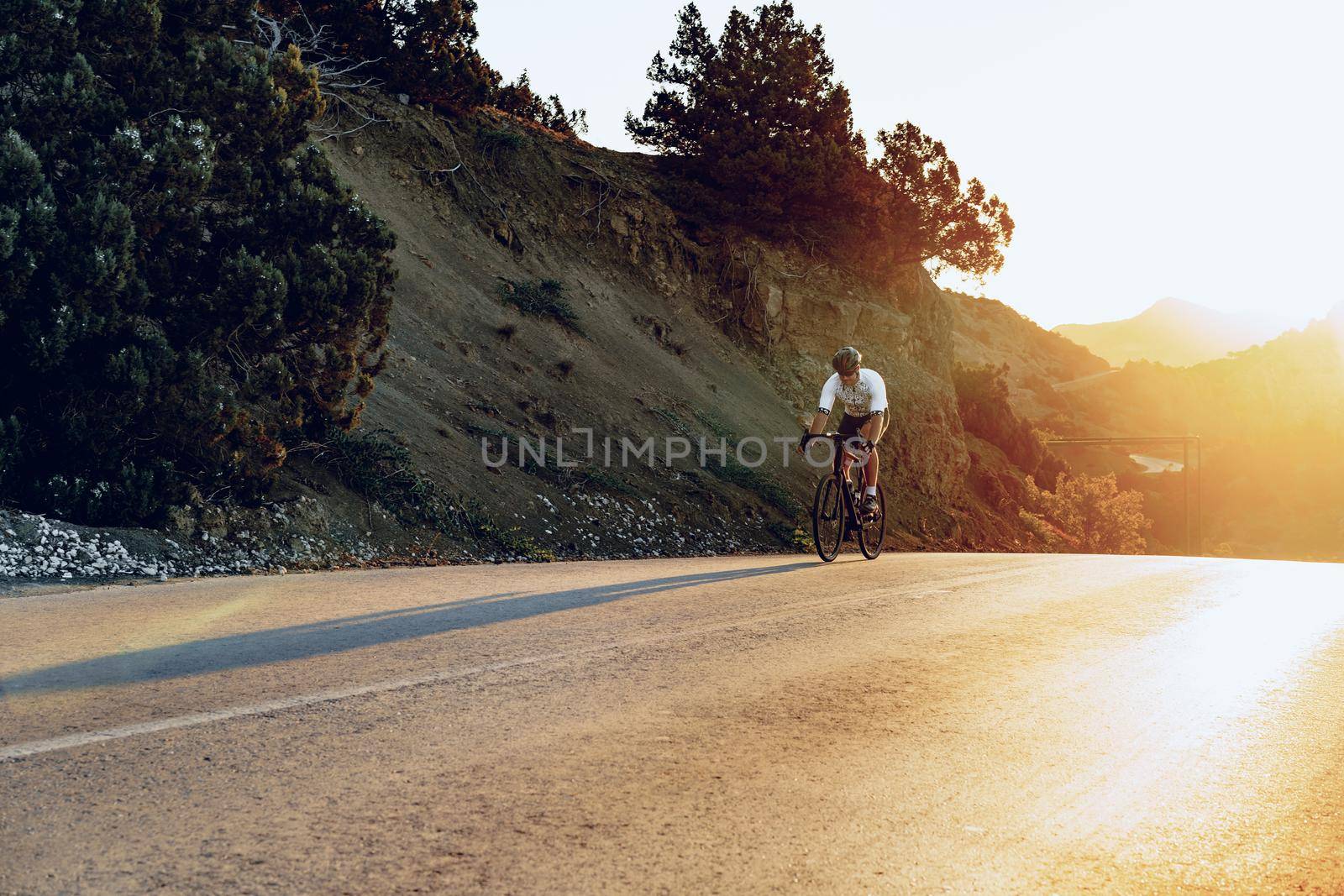Professional man cyclist on a mountain road at sunrise