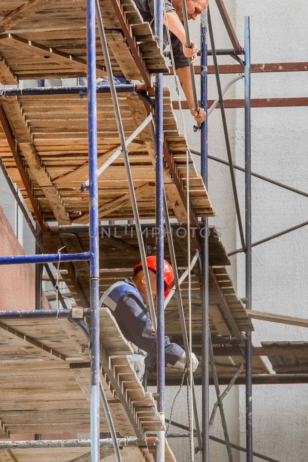 Belarus, Bobruisk - August 21, 2020: Industrial workers on scaffolding near a building in the city, safety work equipment by AYDO8