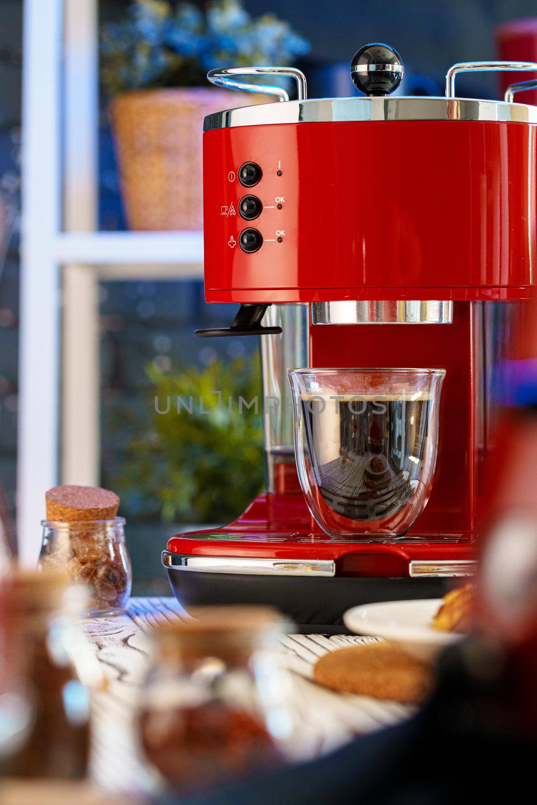 Red coffee machine with a glass on kitchen counter, close up