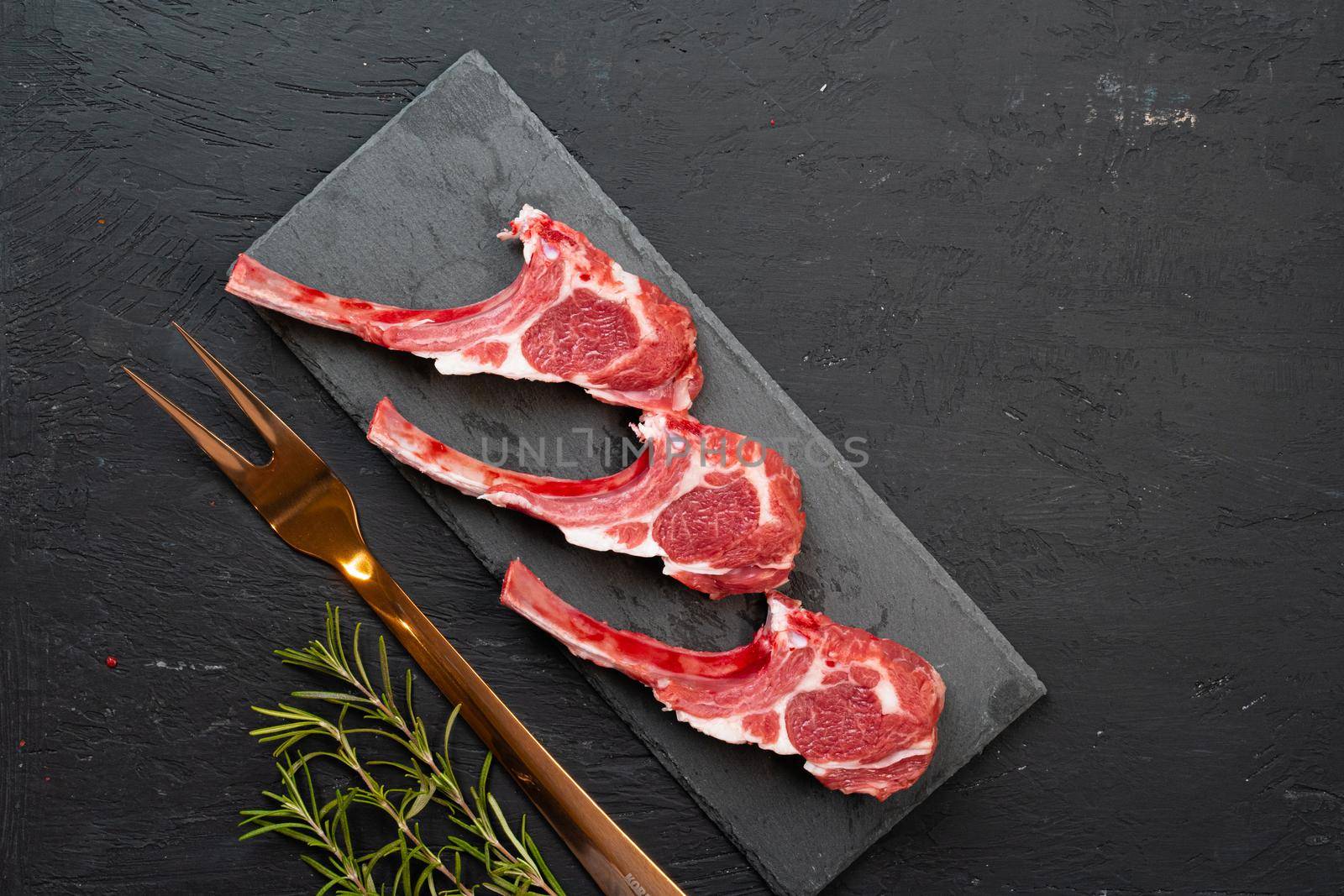 Raw fresh lamb ribs on dark background, close up.