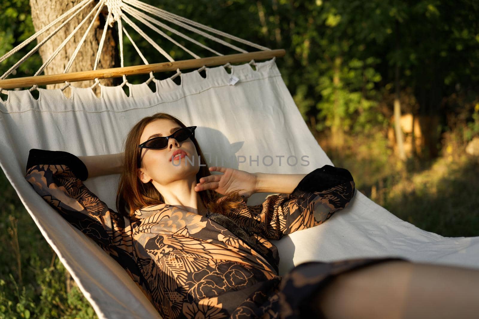 glamorous woman in sunglasses lies in a hammock resting the sun. High quality photo