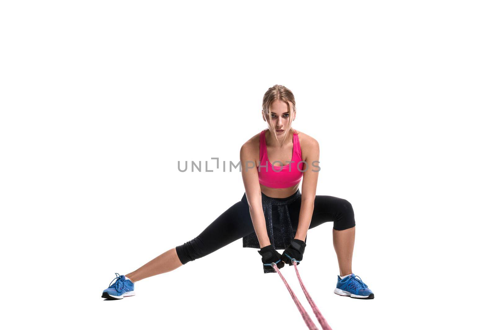 Strong woman using a resistance band in her exercise routine. Young woman performs fitness exercises on white background. Woman with beautiful slim healthy body posing in studio.