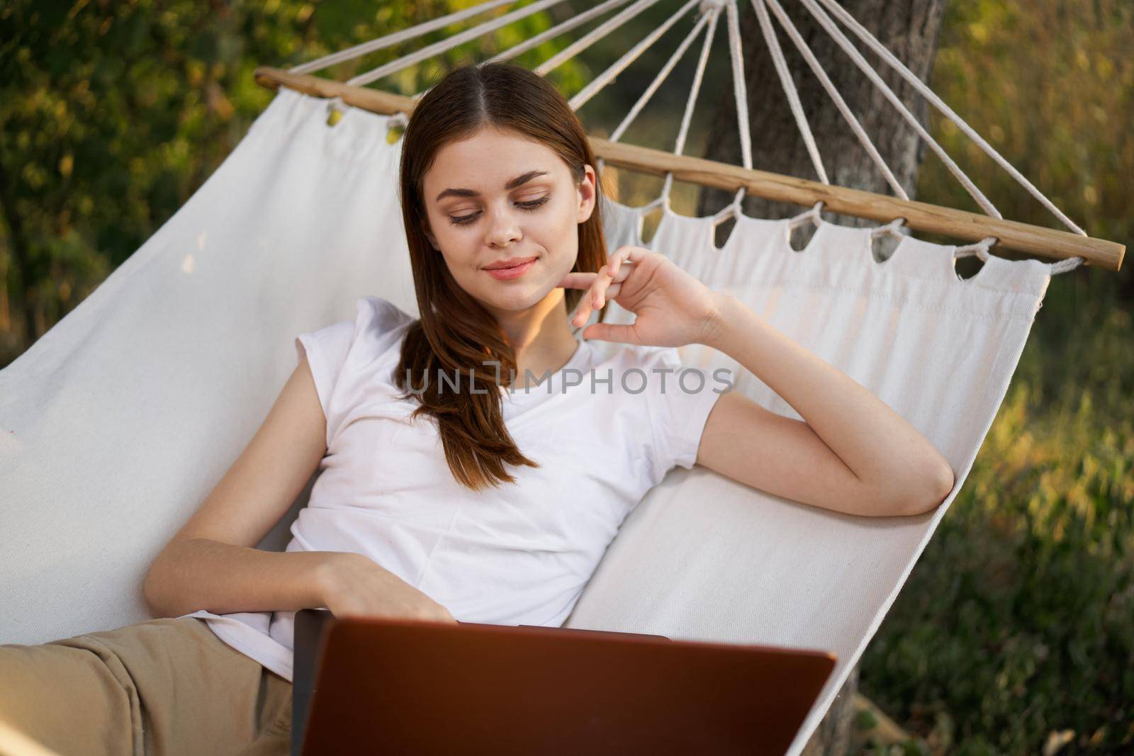cheerful woman lies in a hammock with a laptop freelance nature. High quality photo