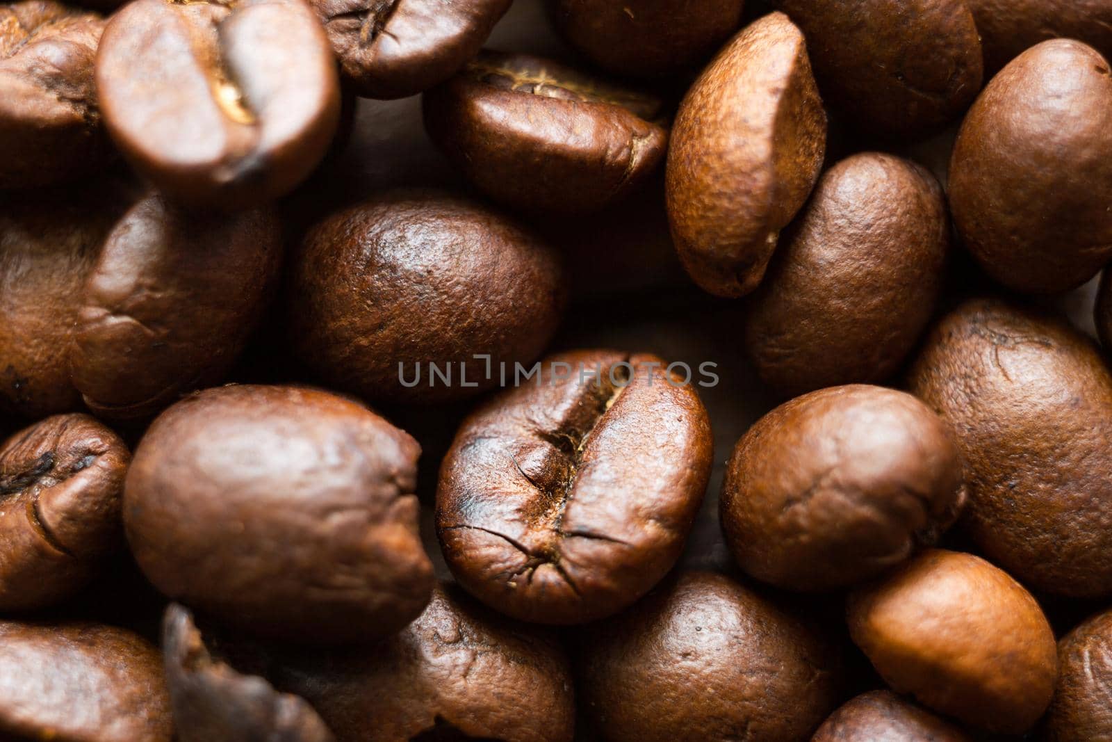 Roasted coffee beans close - up-fragrant background. Brown arabica coffee beans are scattered on the wooden table. Copy space by Simol