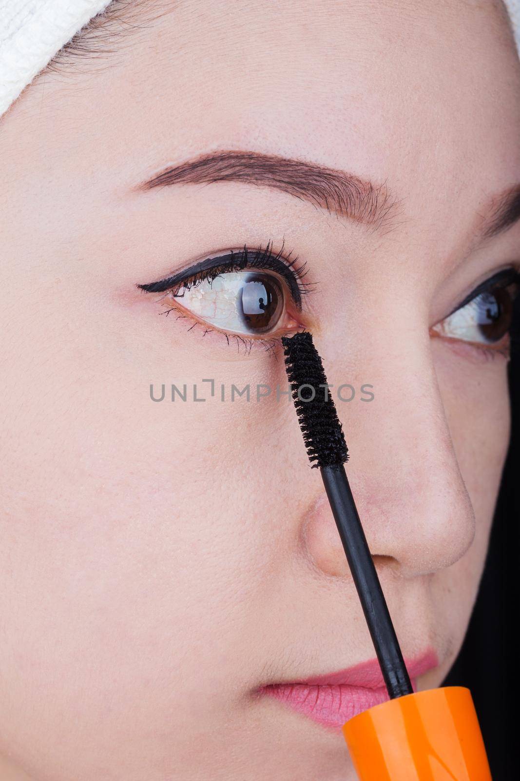 woman applying mascara on her eyelashes by geargodz