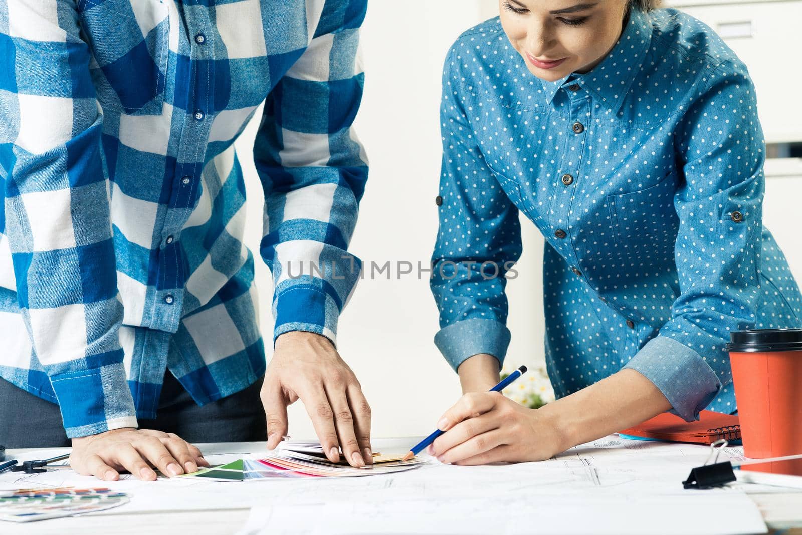 Designers selecting color palette for design project. Human hands, technical drawing and color swatches on desk. Interior design, decoration and renovation. Brainstorming, teamwork and creativity.