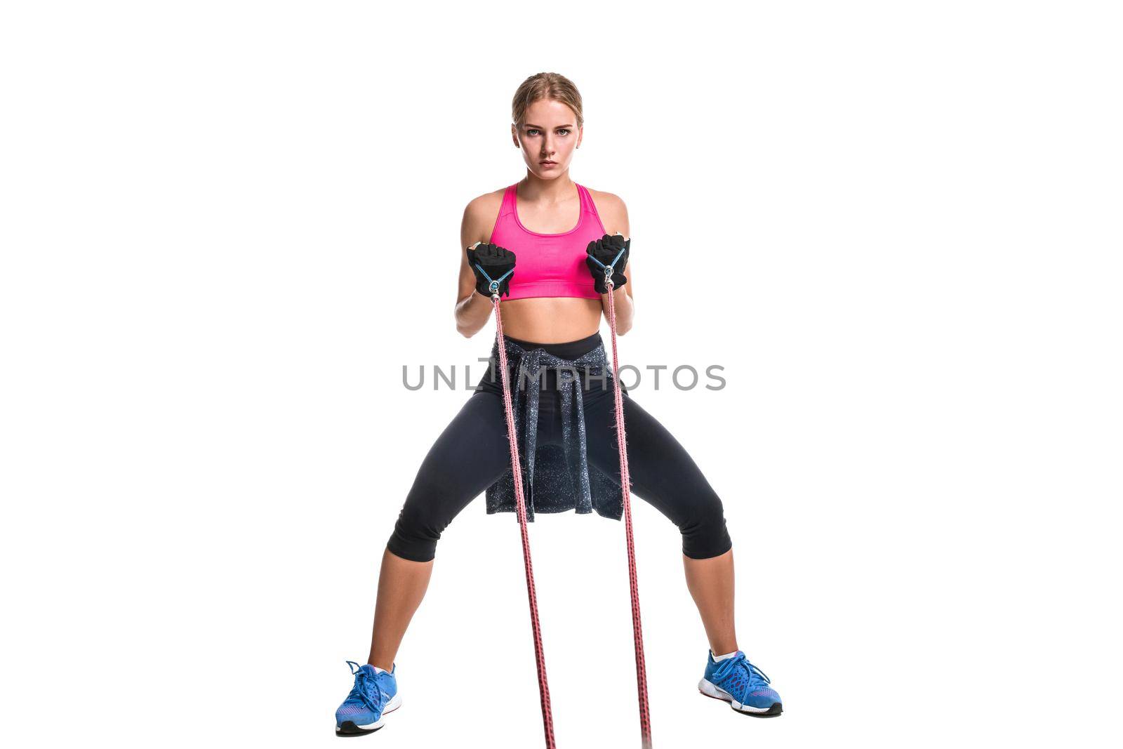 Strong woman using a resistance band in her exercise routine. Young woman performs fitness exercises on white background. Woman with beautiful slim healthy body posing in studio.
