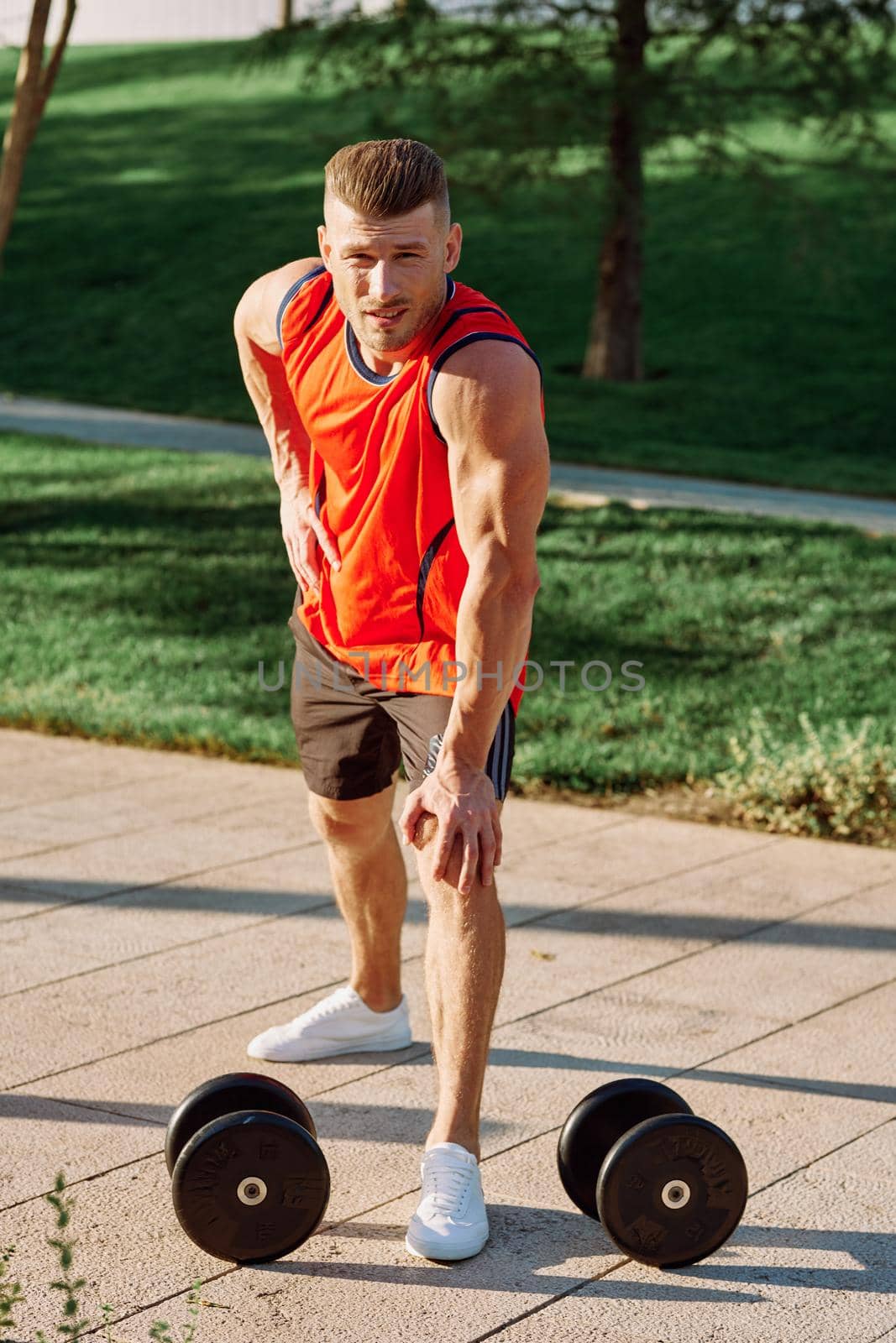 sporty man in the morning in the park with dumbbells exercise. High quality photo