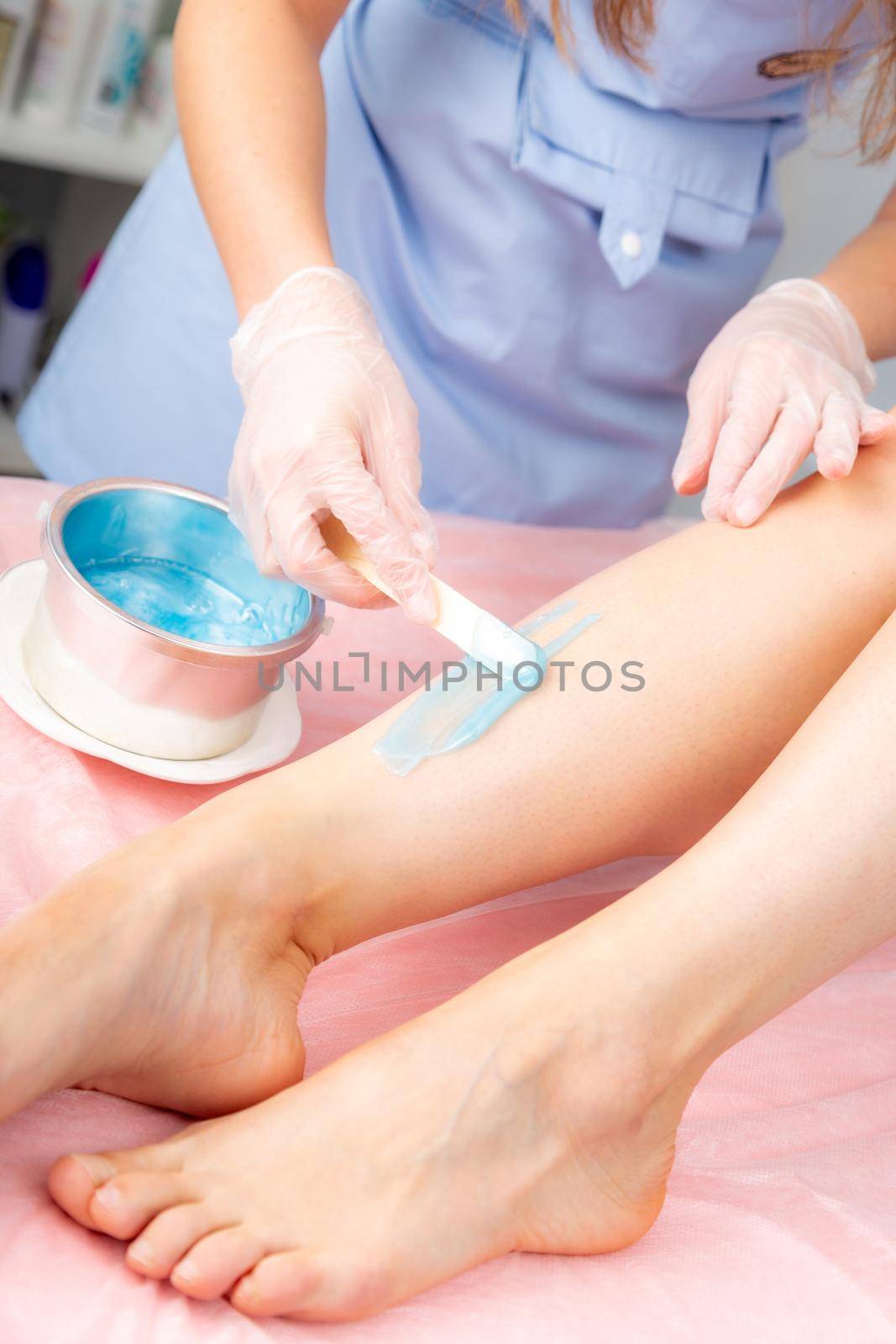 Cosmetology concept. Sugar and waxing depilation of the feet in the beauty salon. Rid of hair on the legs. Sugaring. Master cosmetologist removing hair on the legs. Beautician in the spa center.