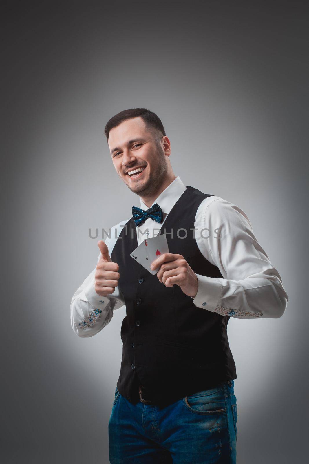 Handsome poker player with two aces in his hands. A man in the studio on a black-and-gray background