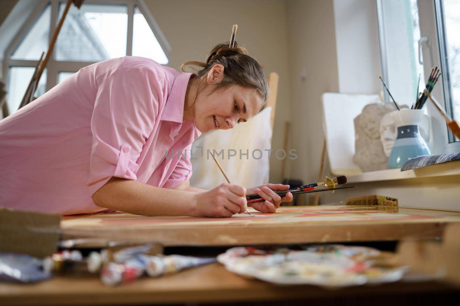 Art, creativity, hobby and creative occupation concept. Bringing creativity to life. Woman painting in art studio. Attractive female artist painting in workshop. Woman hobby, activity, profession by Tomashevska