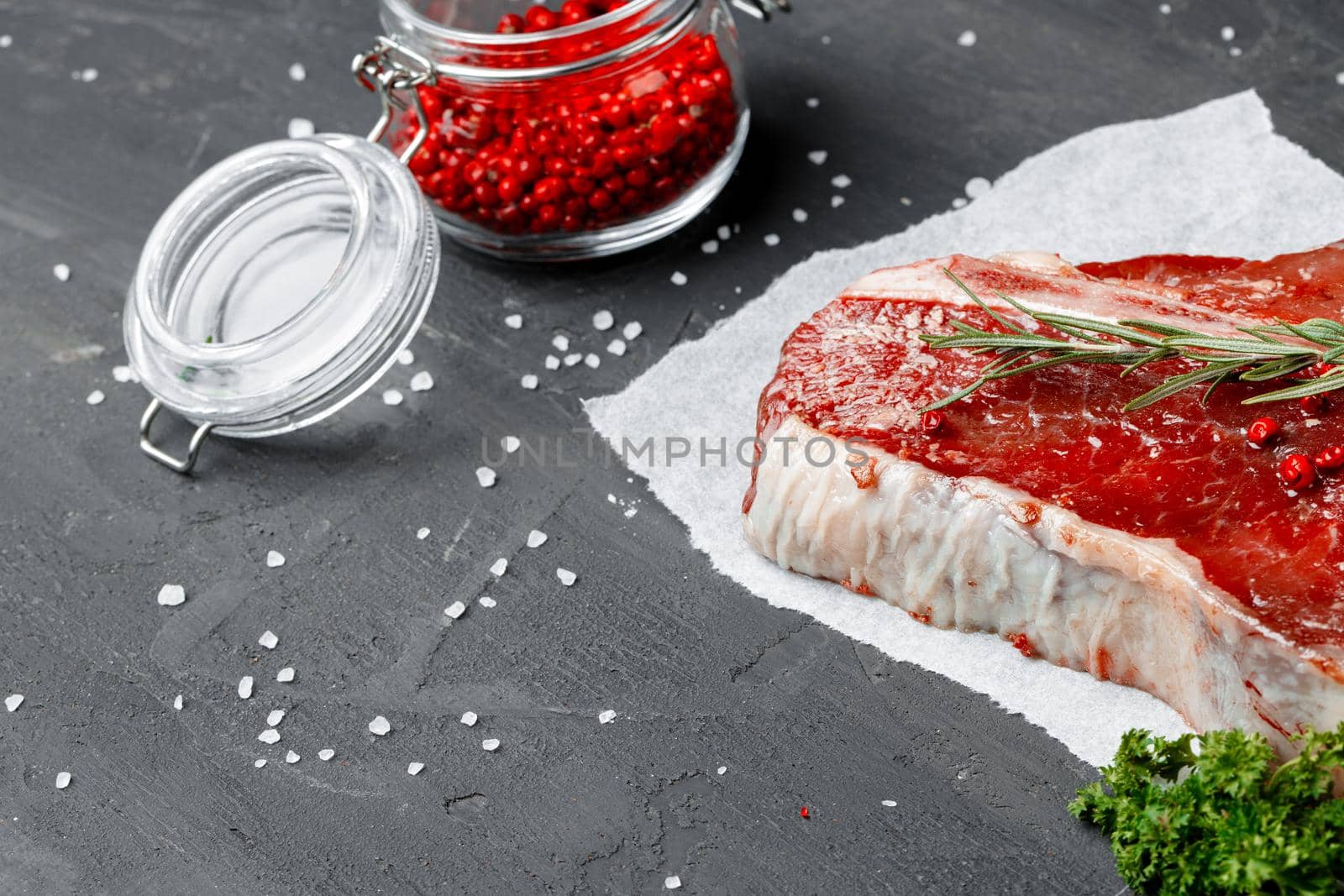 Raw fresh meat t-bone steak with spices on a dark background, close up