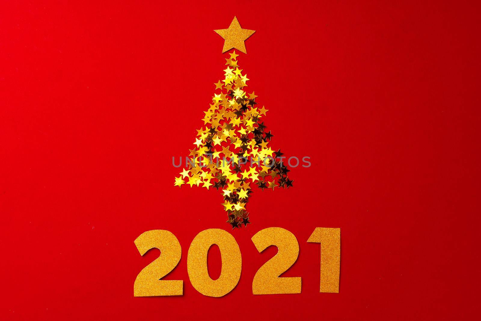 Christmas tree made of gold confetti on red background top view