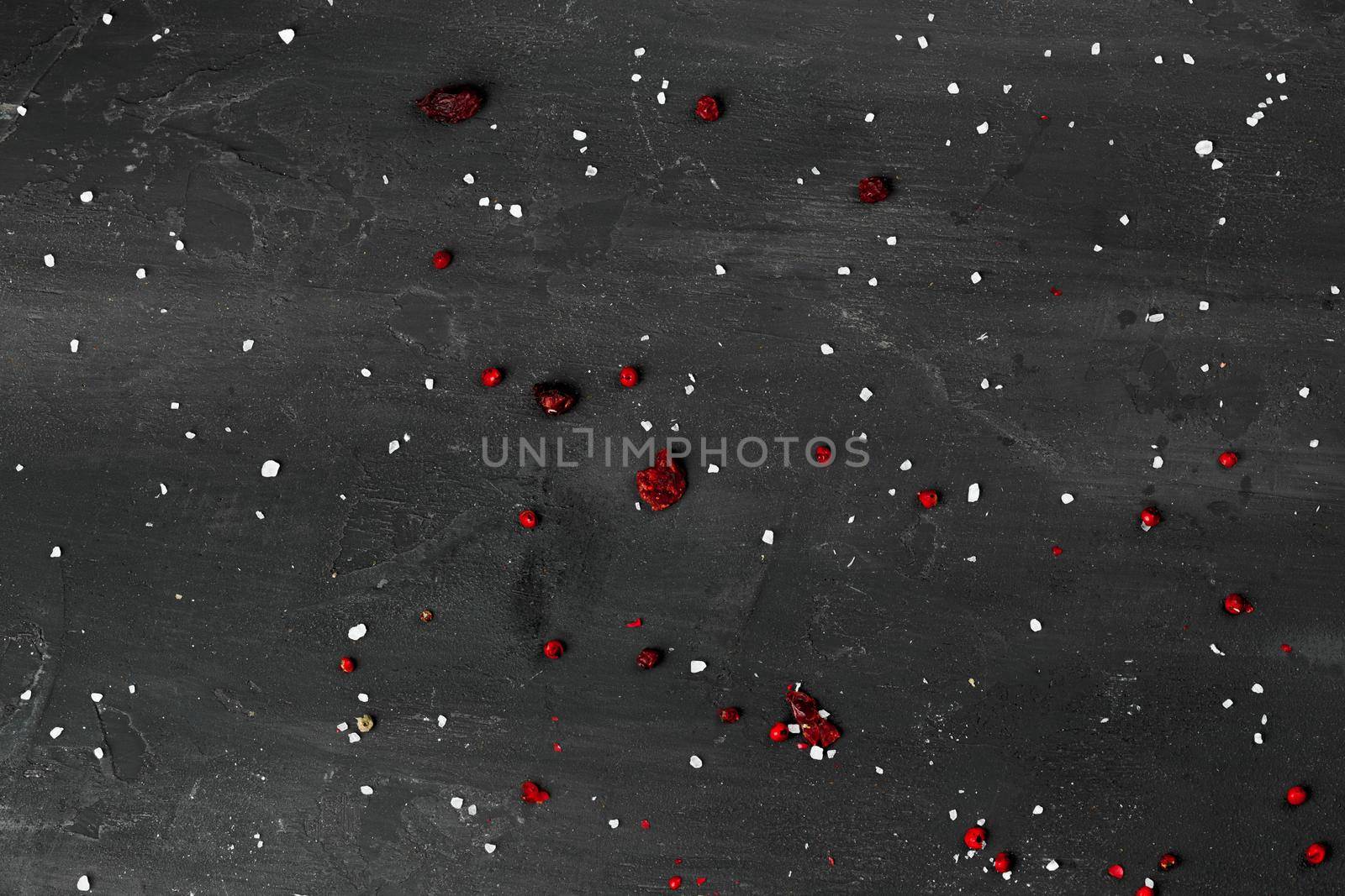 Black stone background with scattered spices, top view, copy space