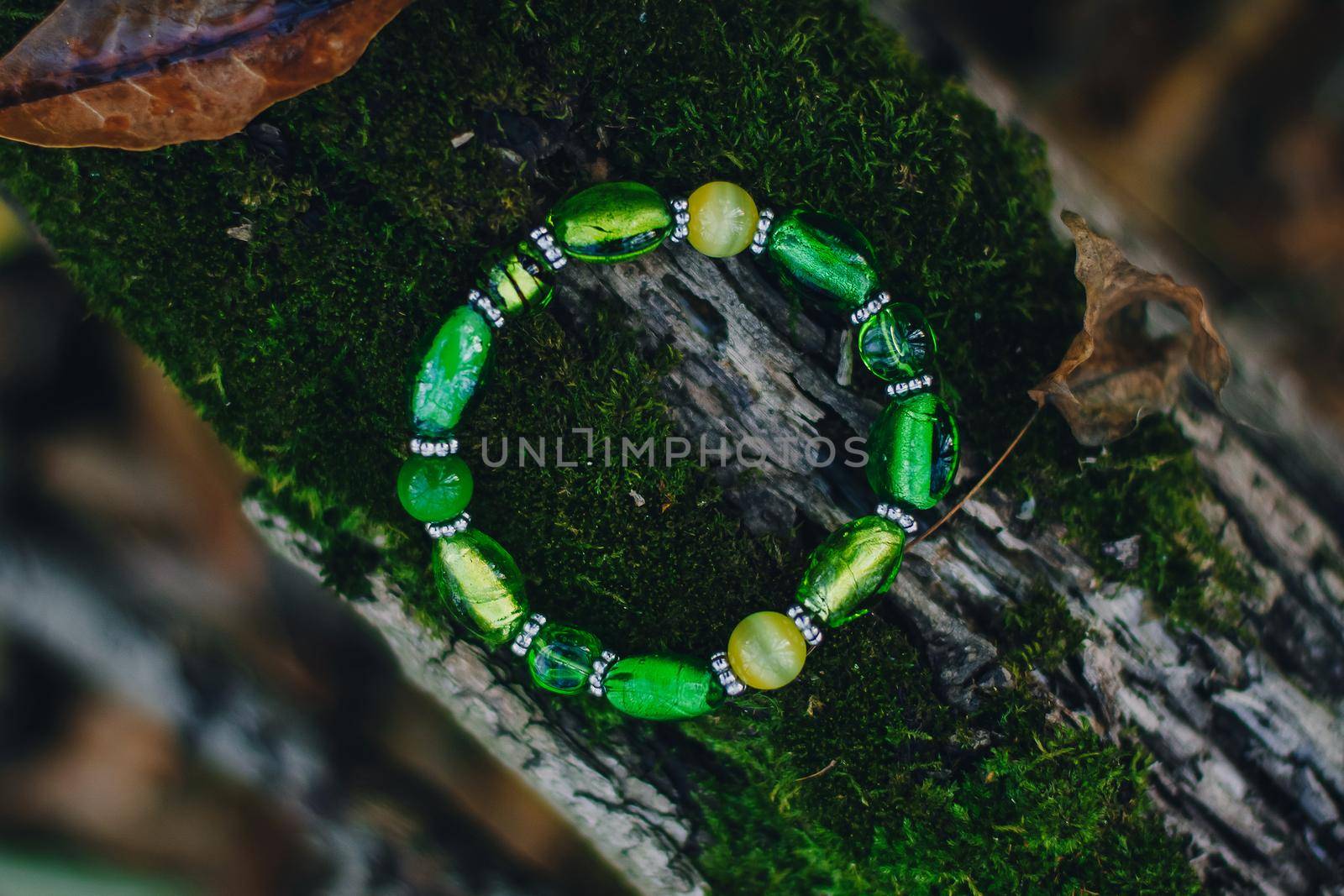 Bracelet handmade handcrafted do-it-yourself glass jewelry on natural wood forest background. Business idea, earning money for a hobby. Useful quarantined skills.