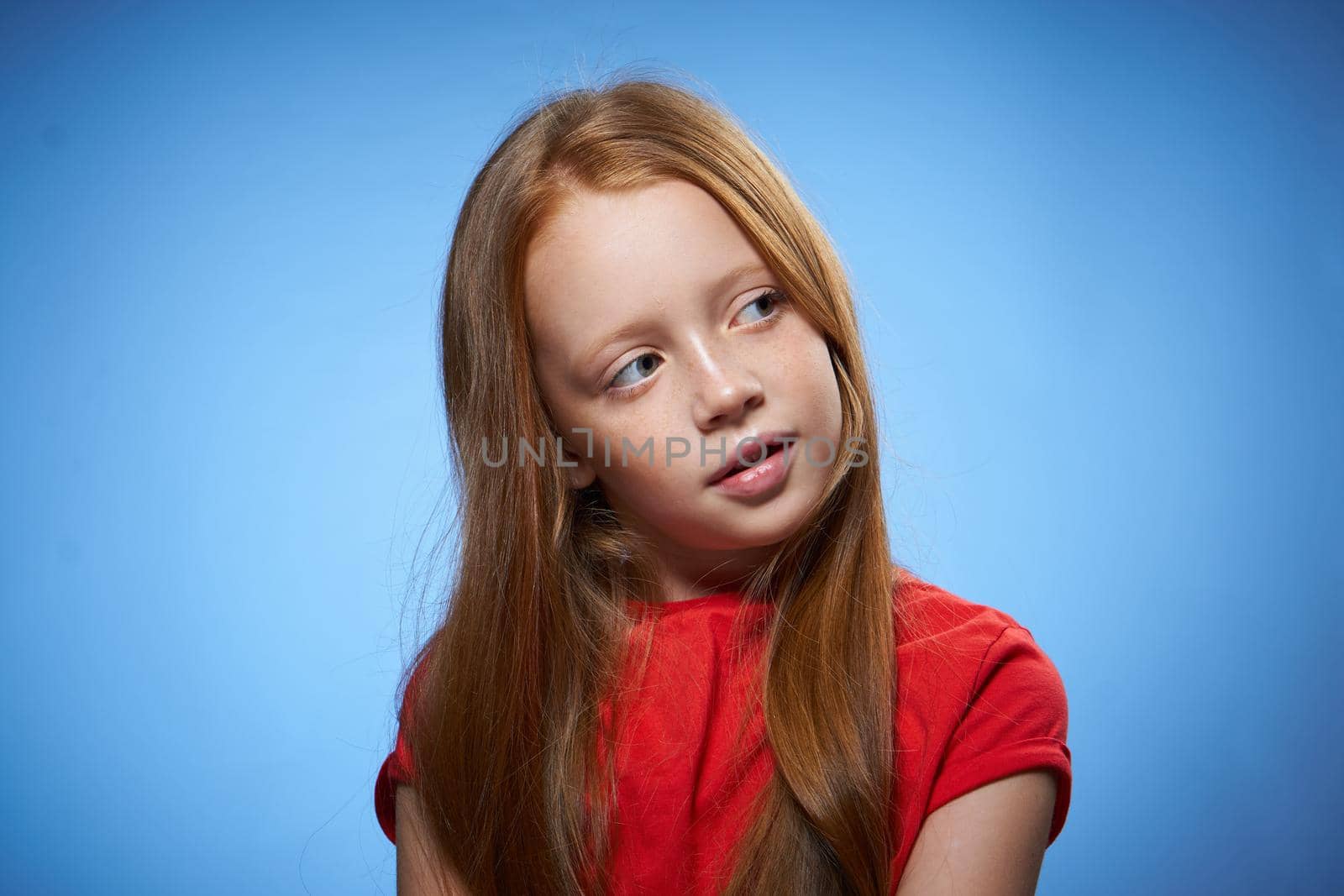 cheerful cute red-haired girl childhood blue background. High quality photo