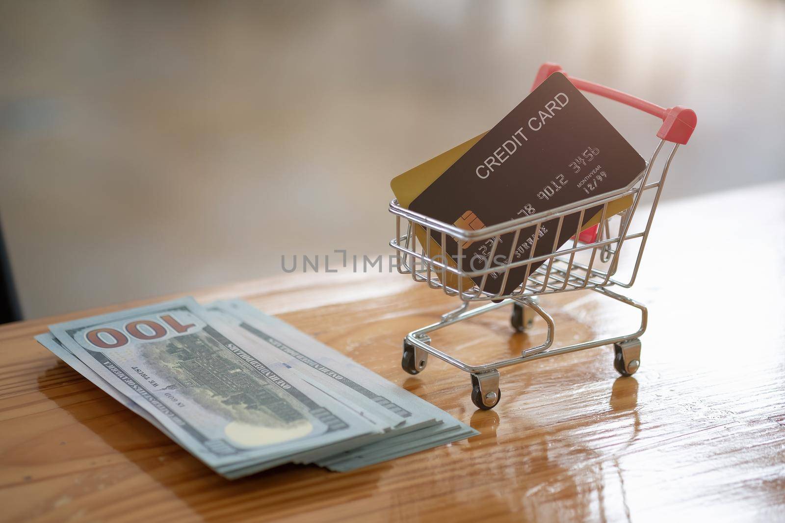 Credit card in mini cart and money bank on wooden desk, online shopping concept.