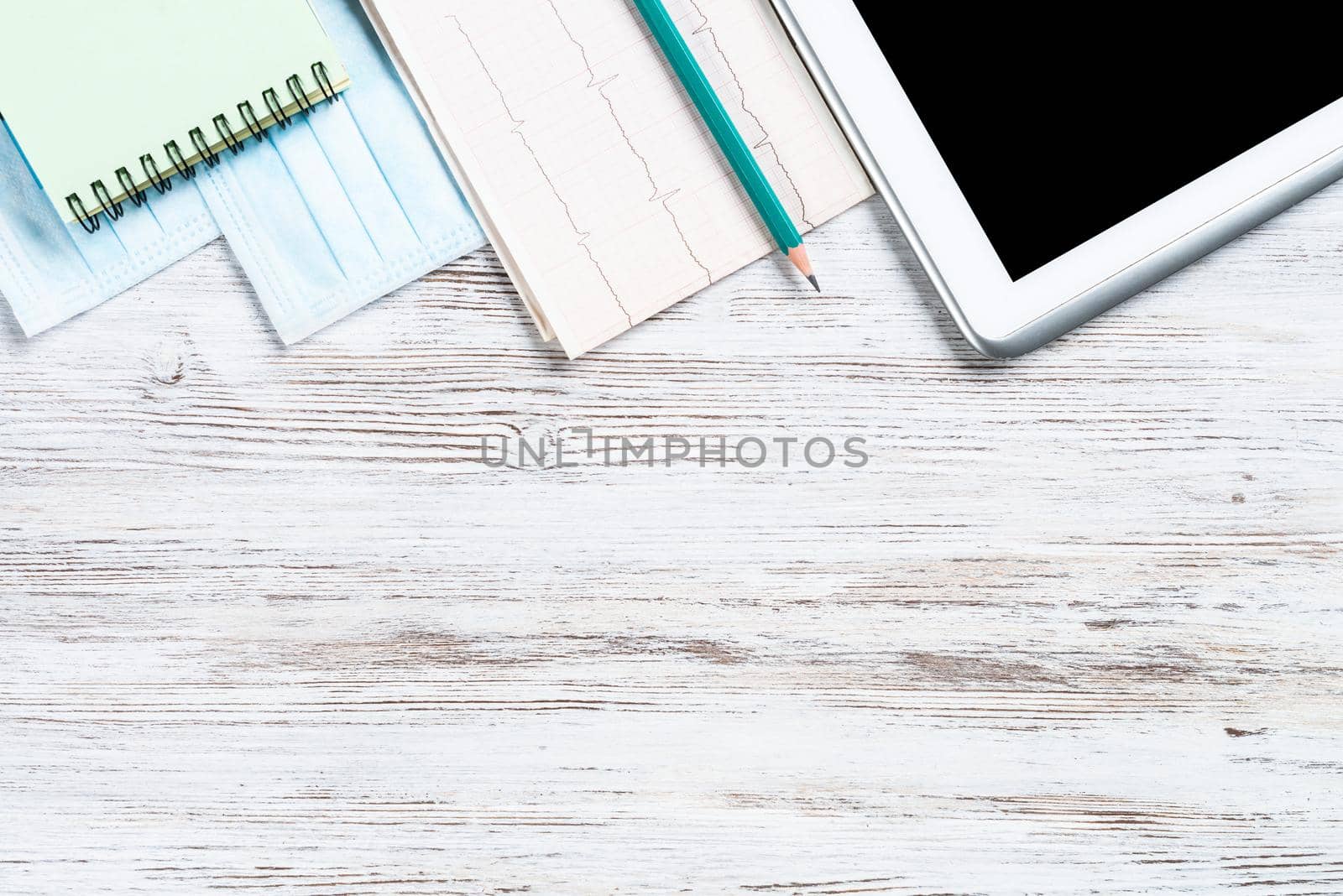 Laboratory patient examination in doctors office. Top view tablet computer and cardiogram on wooden desk. Medical diagnostics and examination in hospital. Healthcare technology concept with copy space