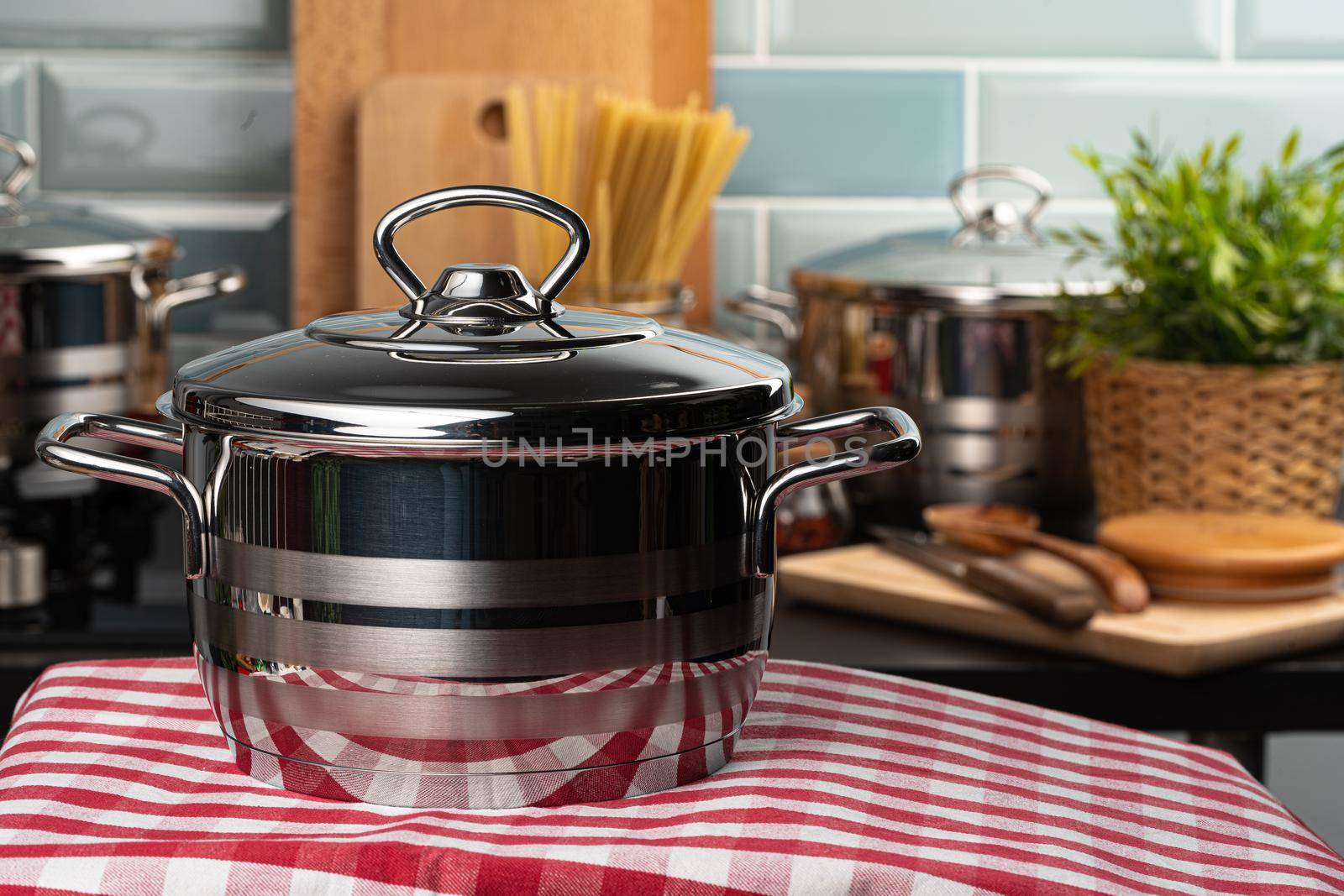 Close up of a new aluminum pot on a kitchen table with checkered napkin