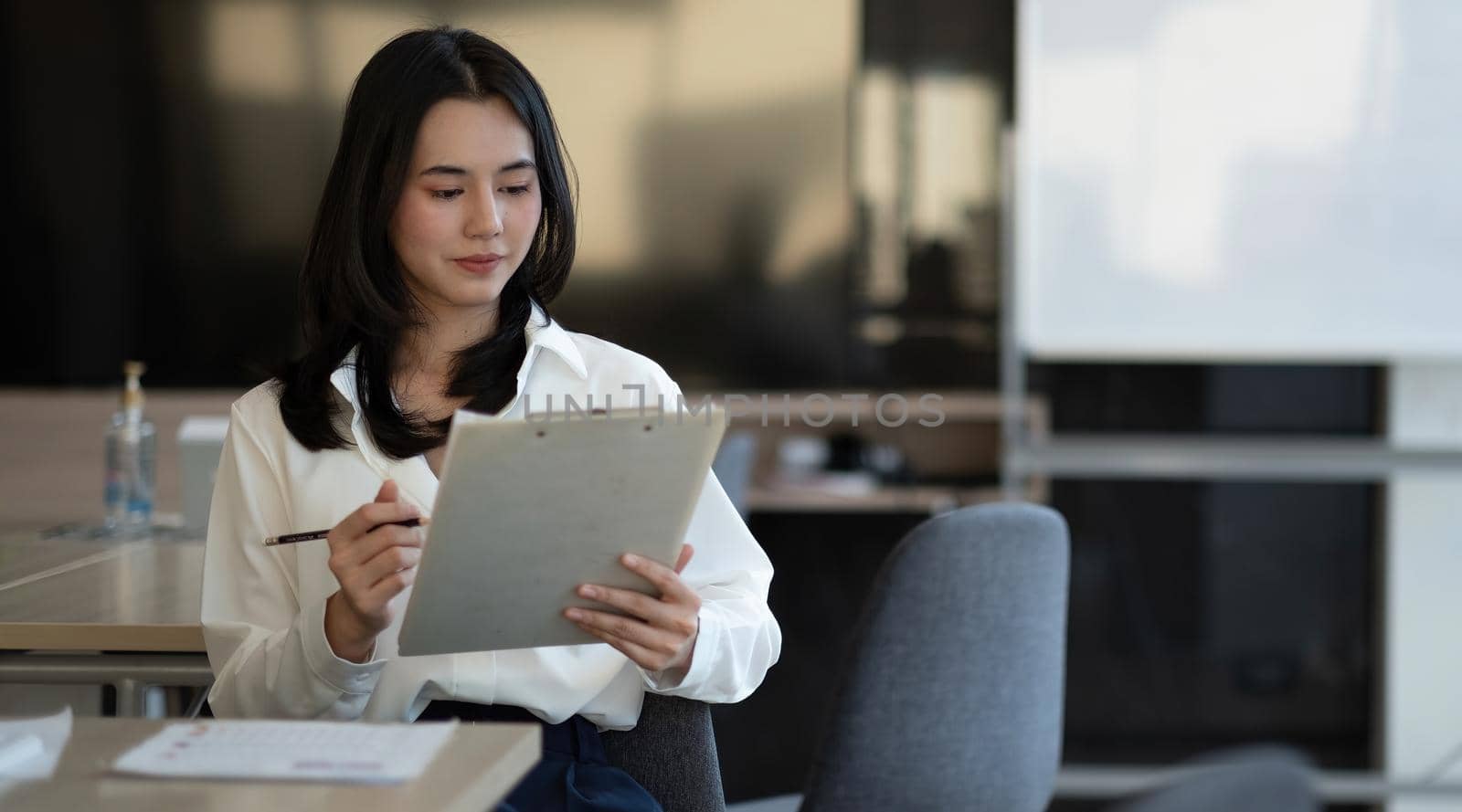 Portrait of successful young Asian businesswoman working with financial report at her office.