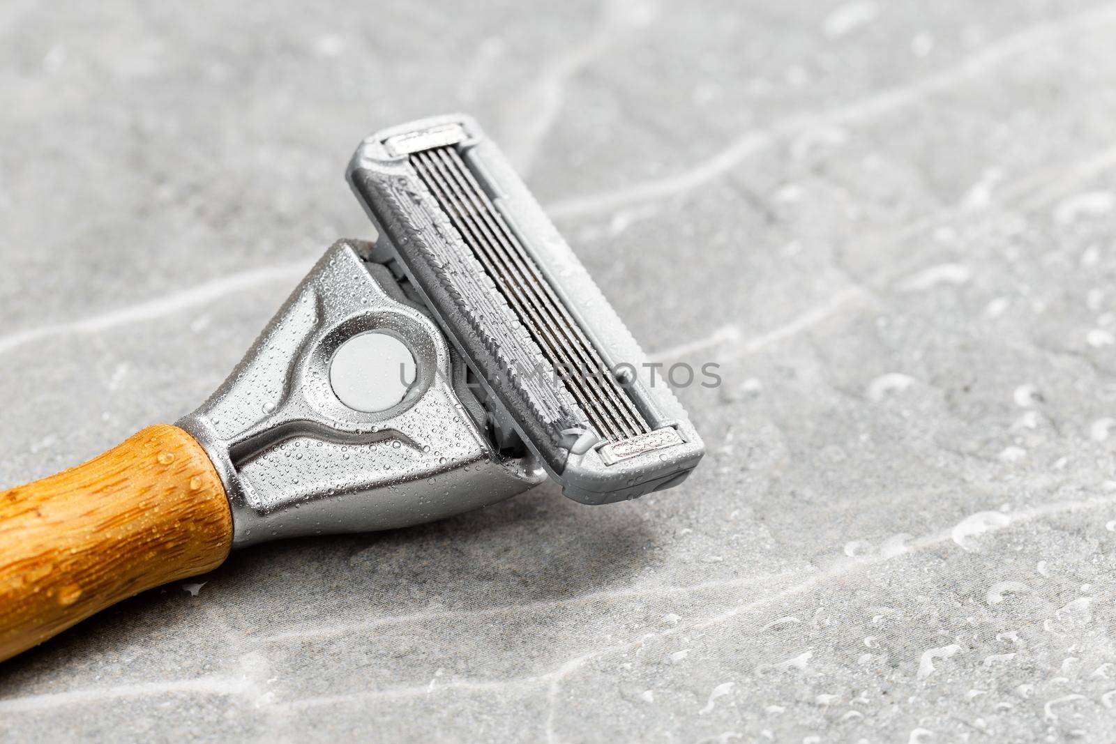 Wet shaving Razor with five blades head and wooden handle on a grey marble background. Macro shot
