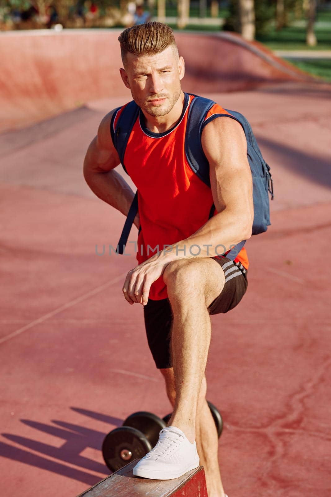 athletic man with dumbbells in his hands outdoors in the park. High quality photo