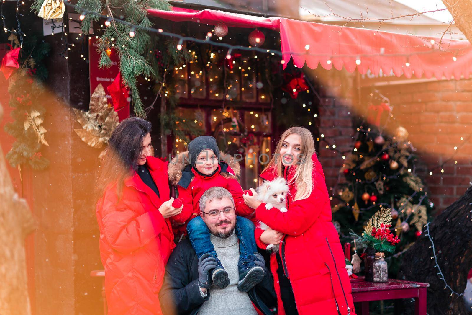 Happy family on the porch of the Christmas decorated house, snowing outdoor. Happy New Year and Merry Christmas. Magic winter