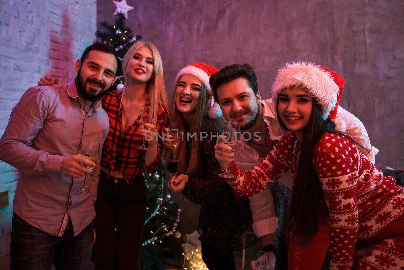 Young people with glasses of champagne at Christmas party. Friends celebrate New Year at home