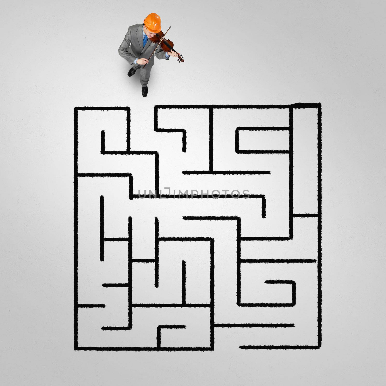 Top view of businessman playing violin and drawn labyrinth on floor
