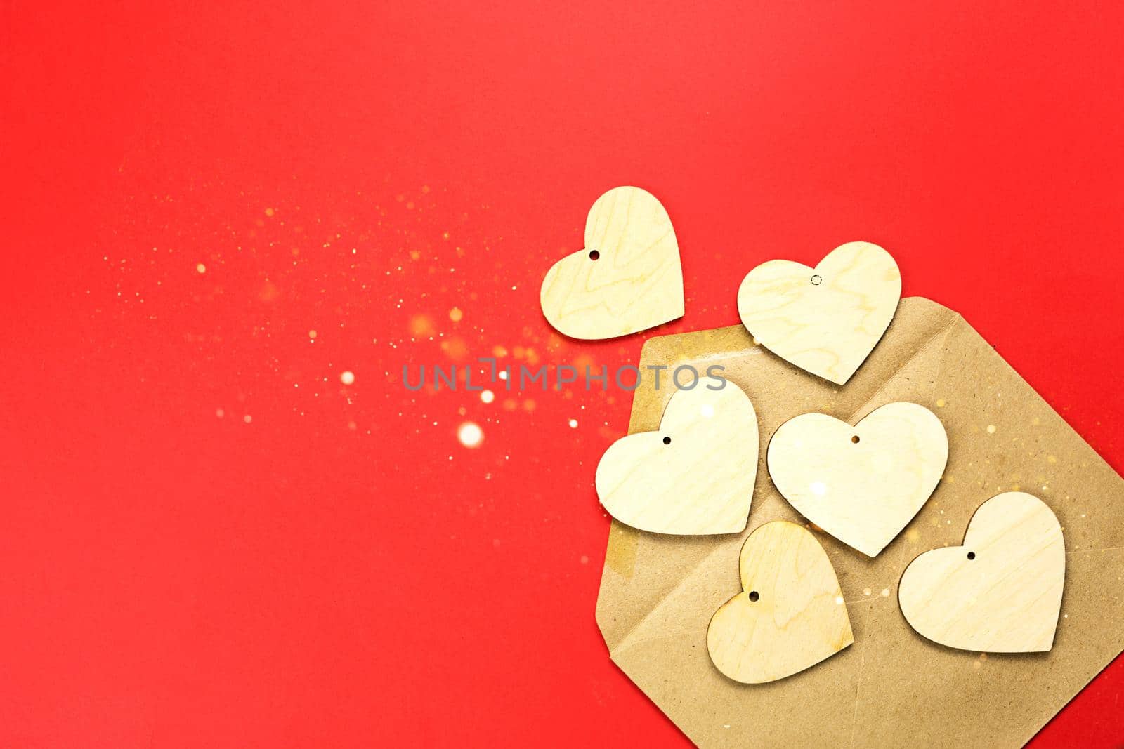 Wooden hearts spill out of an open envelope on a red background. Valentine's Day, love letter, declaration of love, acquaintance. Copy space, mock up