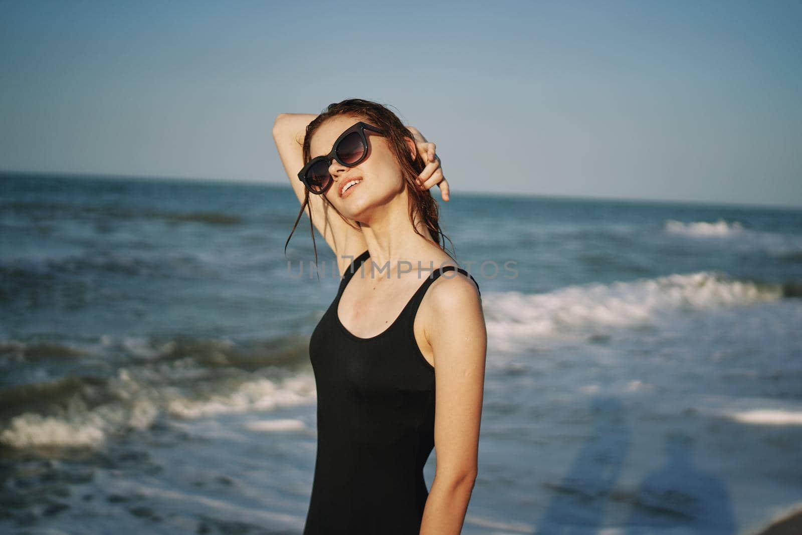 cheerful woman in black swimsuit sunglasses ocean travel. High quality photo