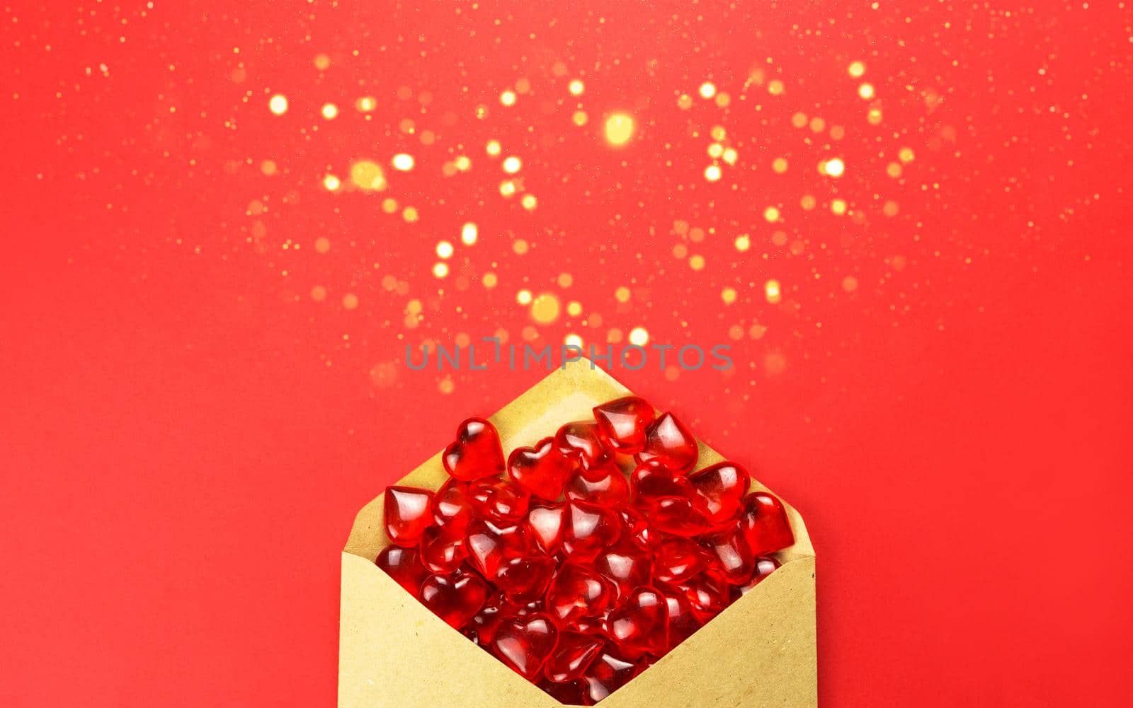 Glass hearts spill out of an open envelope on a red background. Valentine's Day, love letter, declaration of love, acquaintance. Copy space, mock up