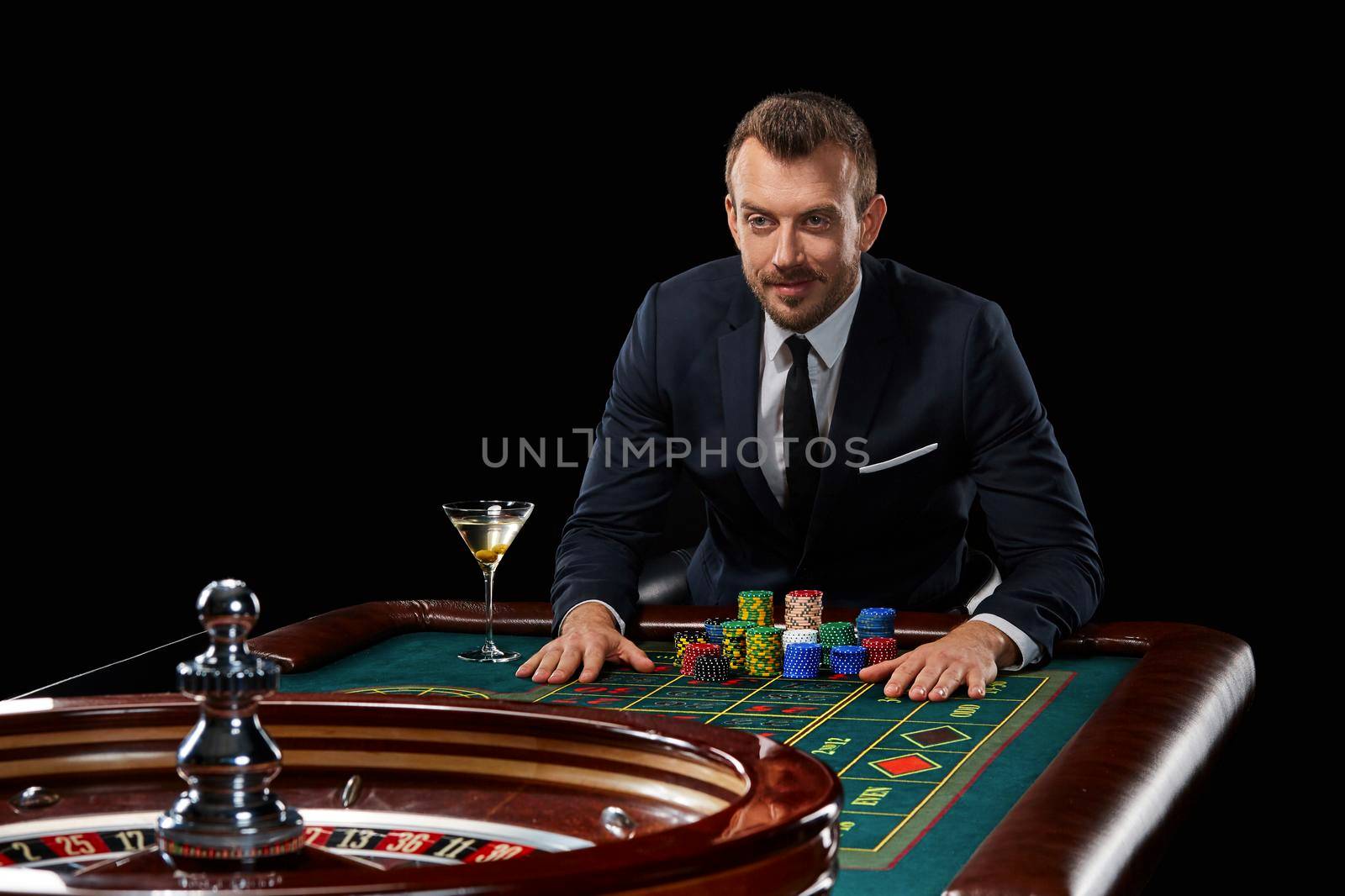 man in a suit playing roulette. addiction to gambling. In the hands of a glass. tensely watching, waiting for the result
