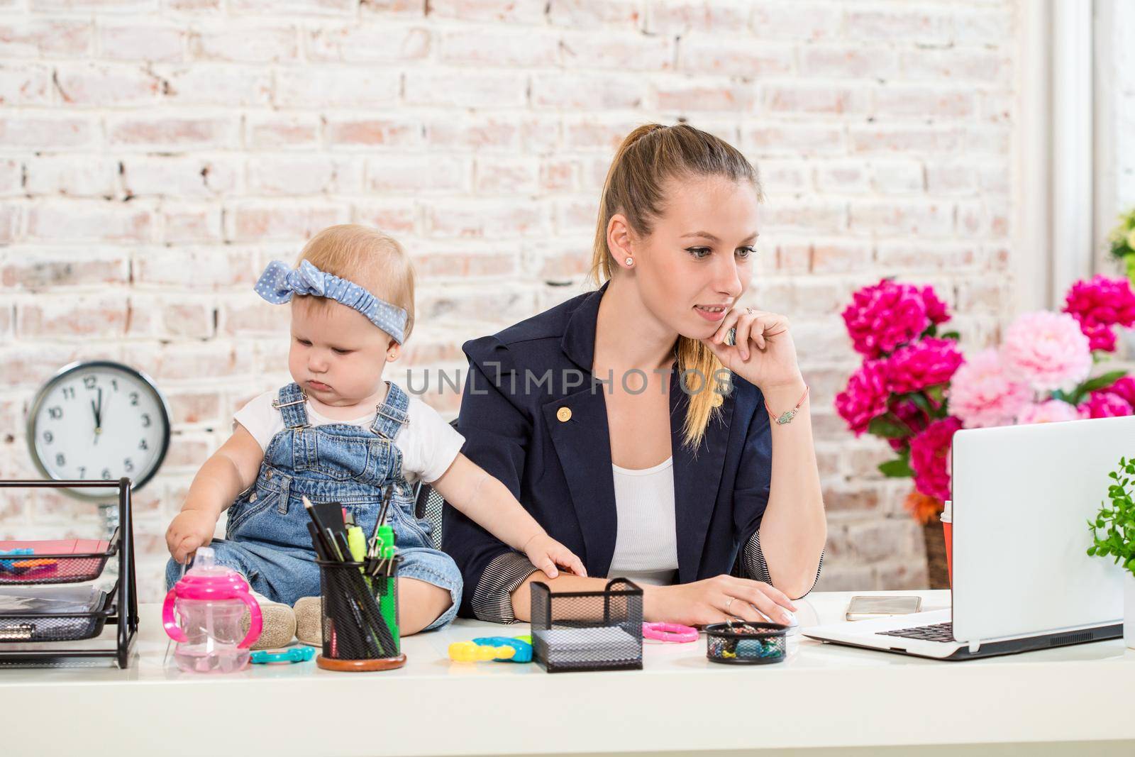 Businesswoman mother woman with a daughter working at the laptop. At the workplace, together with a small child