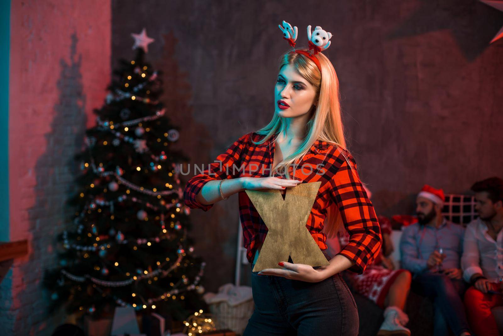 Christmas, x-mas, New year, winter, happiness concept - smiling woman in santa helper hat with a wooden letter X. Funny people. Christmas party at home