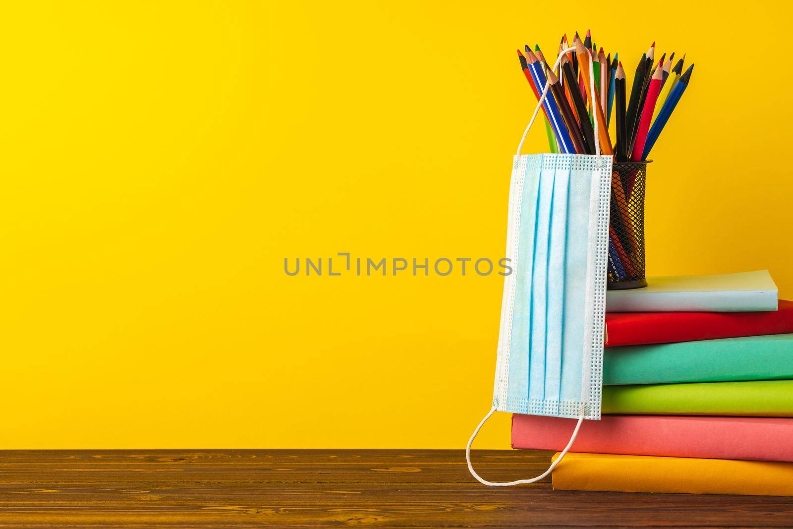 School supplies and medical face mask, front view, coronavirus concept