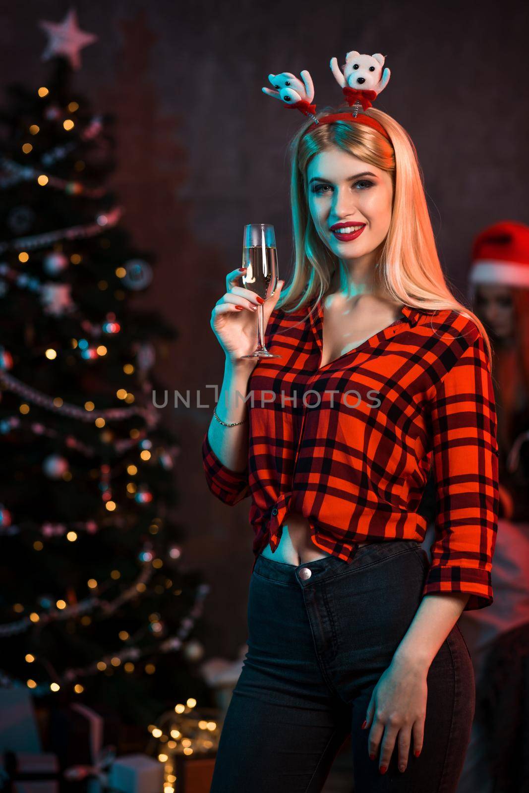 Beautiful young woman with glass of champagne at Christmas party by nazarovsergey