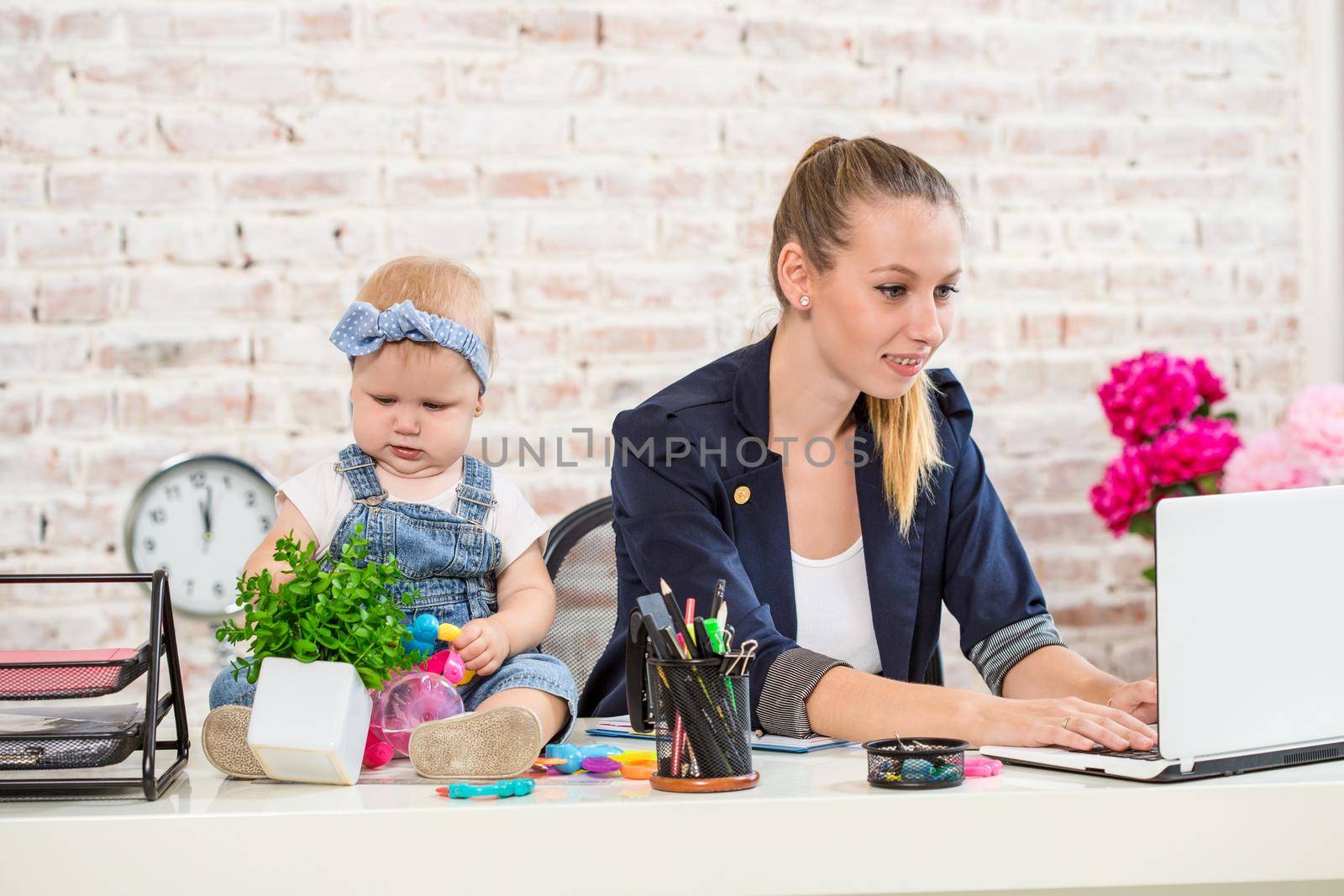 Businesswoman mother woman with a daughter working at the laptop. At the workplace, together with a small child