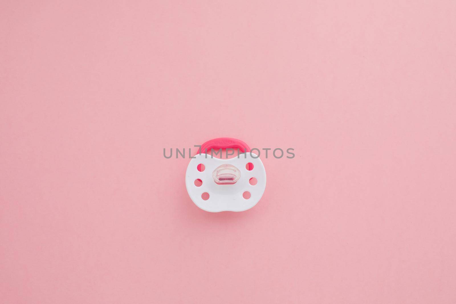 Baby pink pacifier with rubber soother isolated on pink background