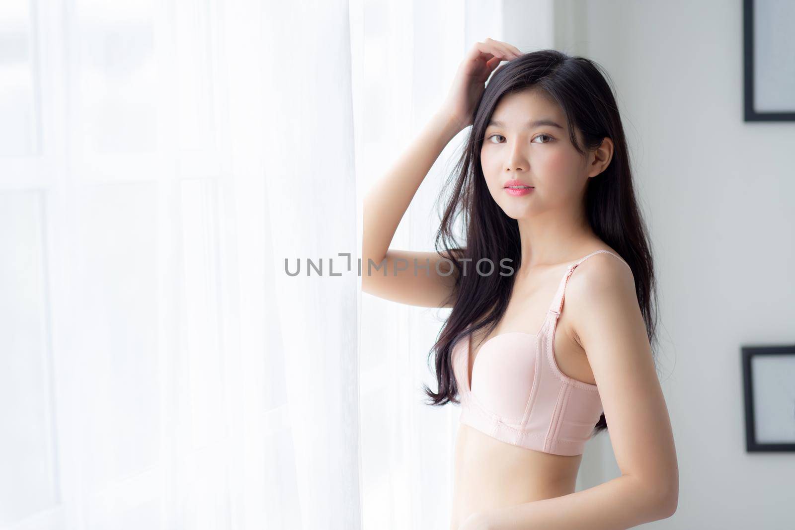 Beautiful portrait young asian woman sexy standing the window and smile while wake up with health, body of girl happy with freshness and cheerful with wellbeing, lifestyle and relax concept. by nnudoo